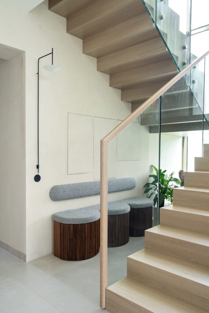 The staircase, where a floating oak cantilever meets a fluted-wood bench, treats circulation as a space worth pausing in