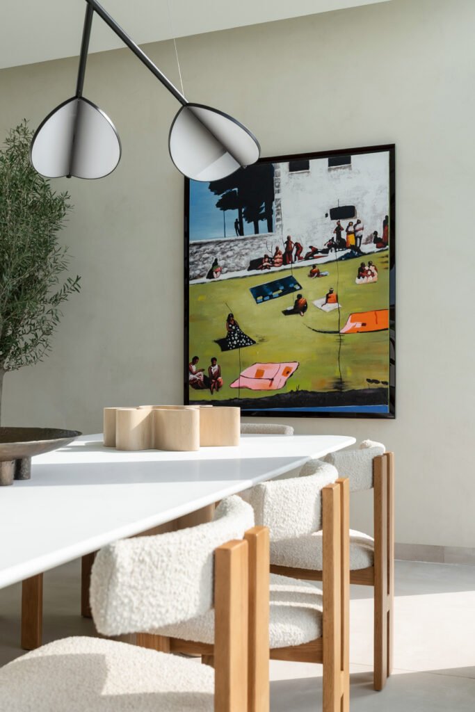 The dining area: a figurative canvas of bathers anchors a composition of stone, bouclé and matte-black conical pendants