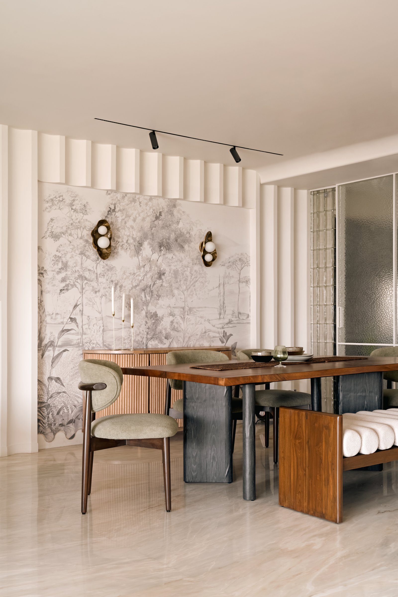 Closer to the table: cane-fronted credenza, organic brass-and-glass sconces, and a wood-and-blackened-base table