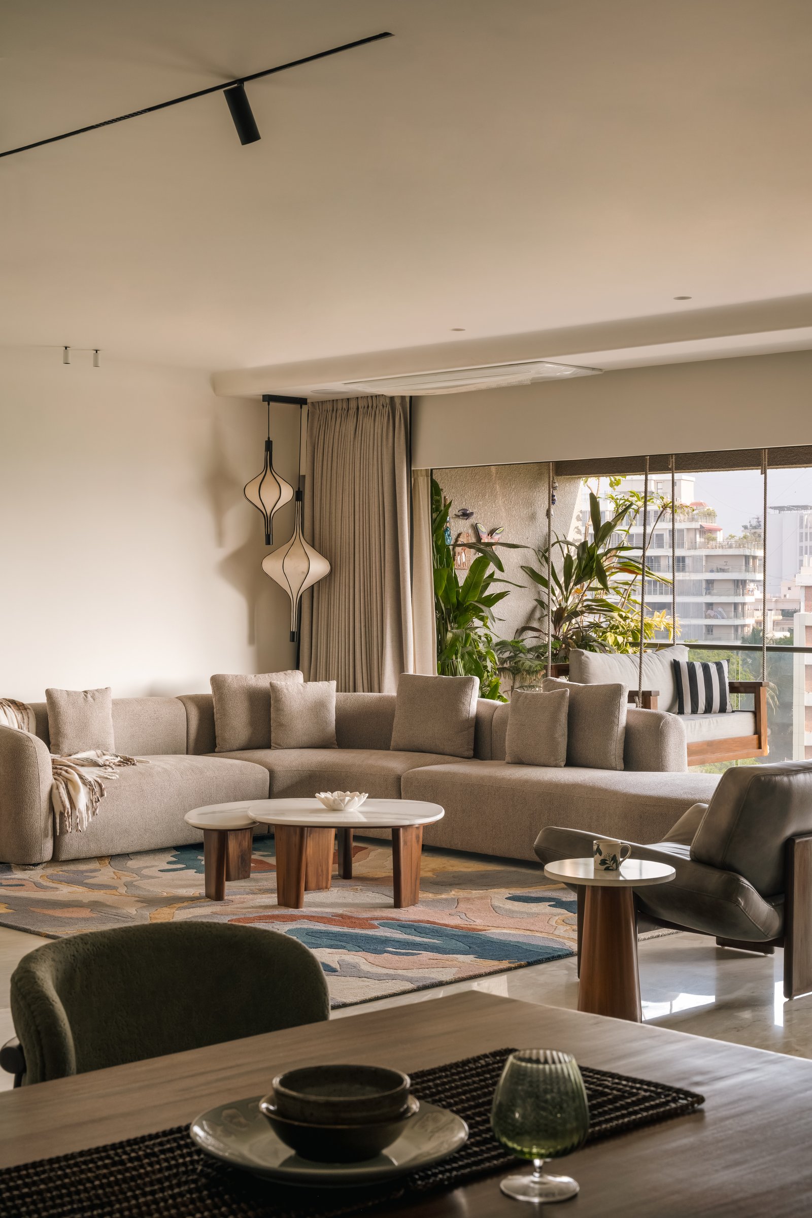 The living room: an oatmeal sectional anchored by an abstract hand-tufted rug, with onion-form pendants softening the corner