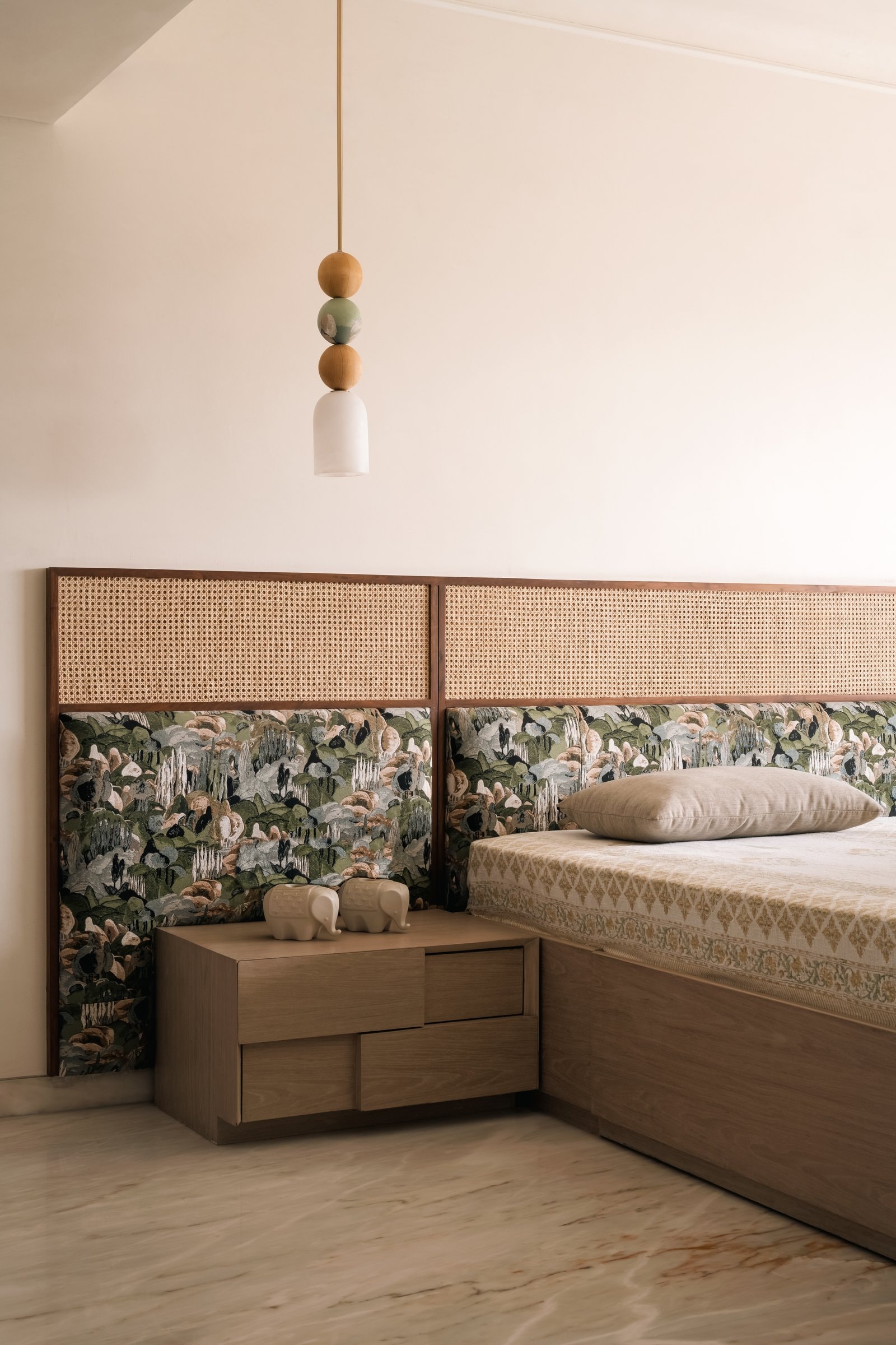 The master bedroom's custom headboard pairs woven cane with a printed botanical panel, the home's only patterned indulgence