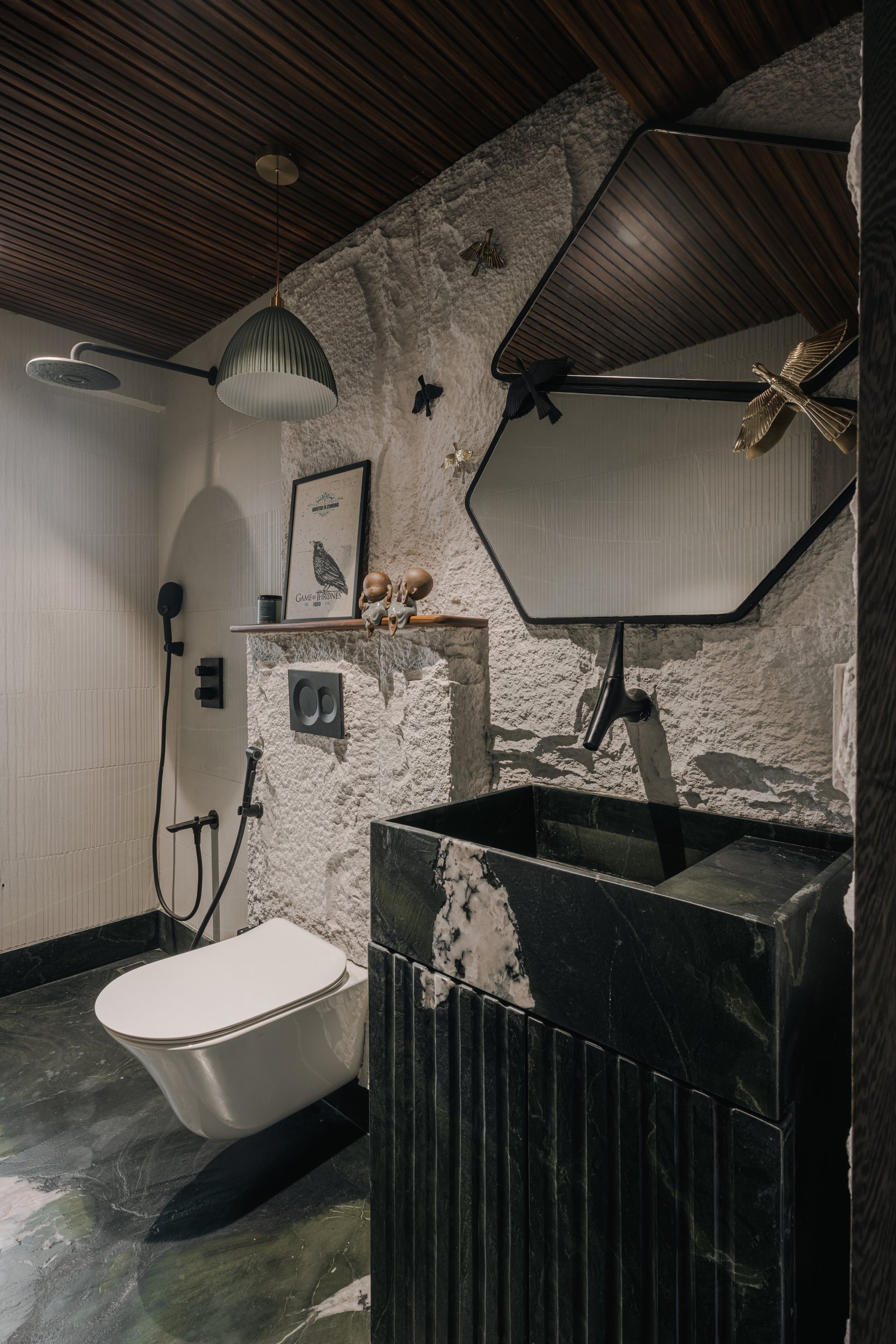 The powder room: a rough white stone wall, a wood-slatted ceiling and a fluted dark green marble basin