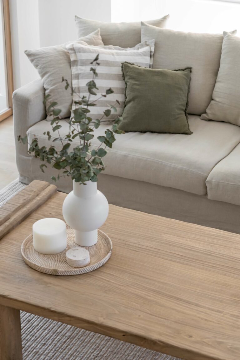 The coffee table vignette: rattan tray, ceramic vase, eucalyptus stems; the project's restraint distilled into a single still life