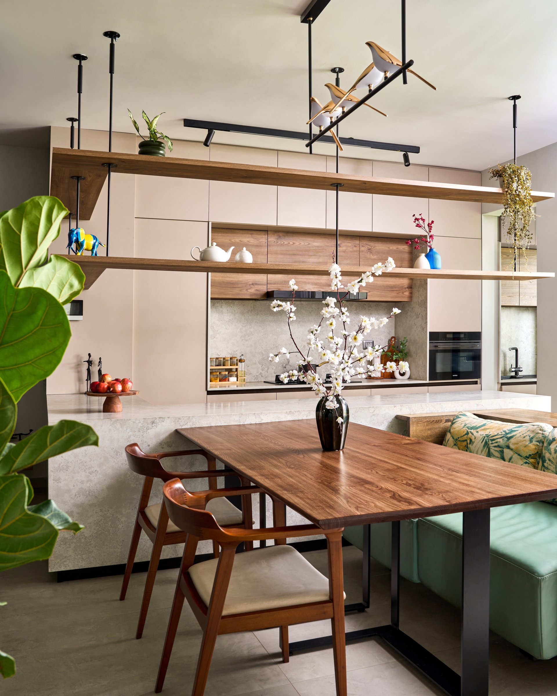 The dining zone, where a walnut table and integrated green banquette anchor the social spine of the home