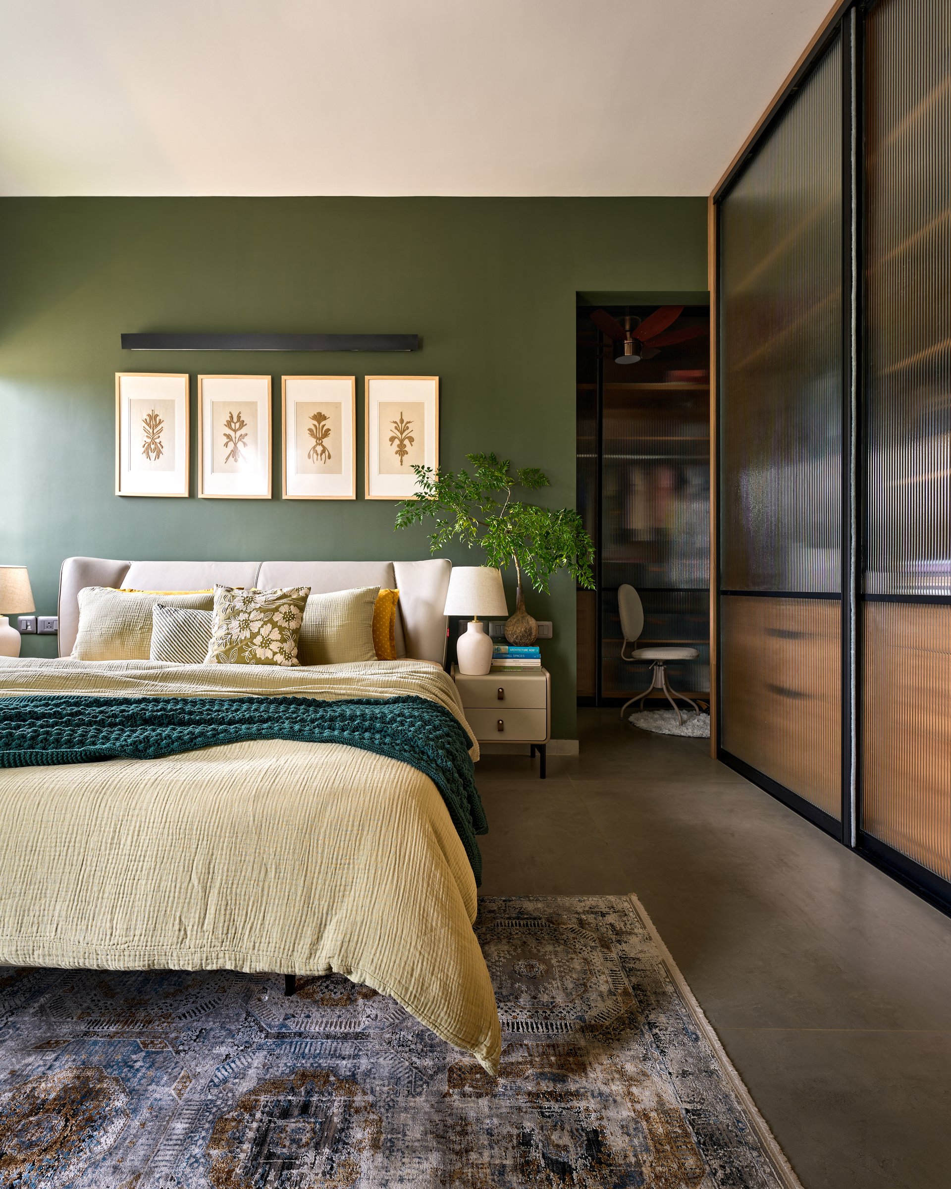 The principal bedroom, colour-drenched in muted green and grounded by a vintage-toned rug