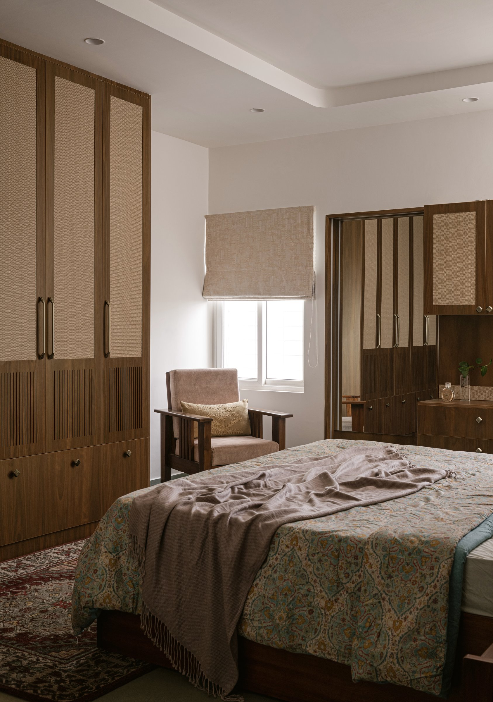 The second bedroom, where pale wood wardrobes with cane and reeded inserts hold the room's restful register