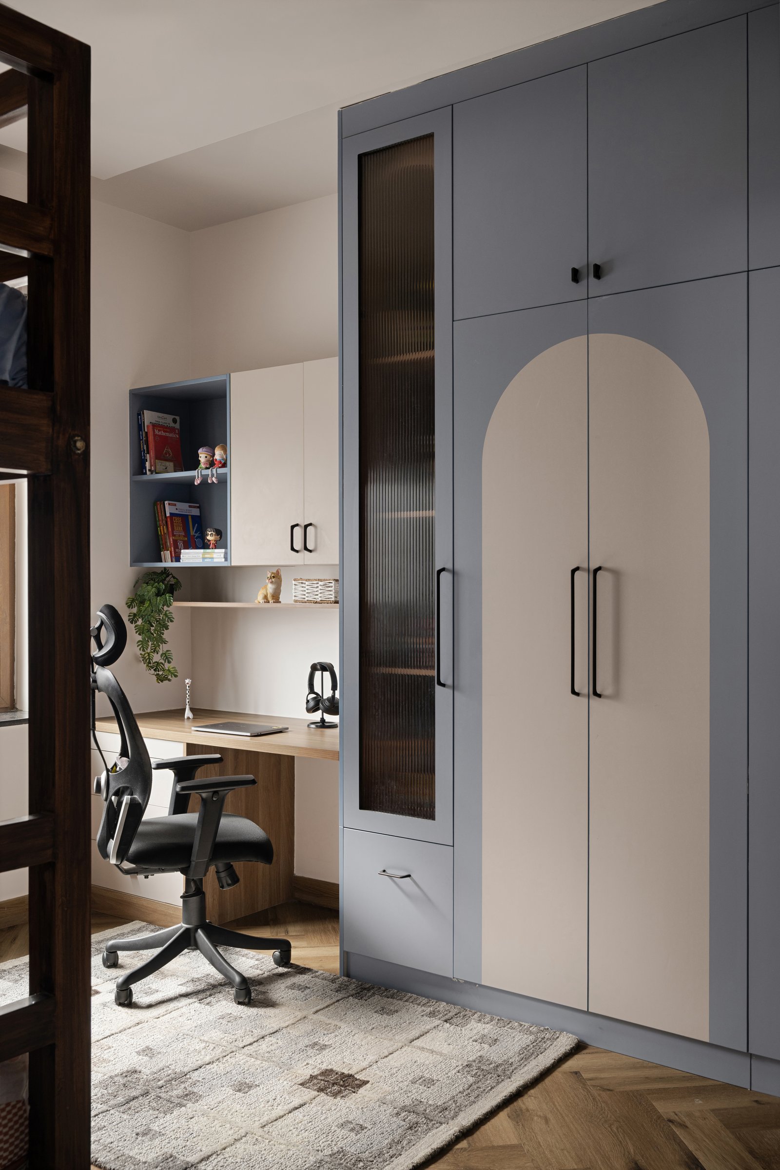 The study and arched wardrobe seen together, the room's cooler palette held by warm wood and powder blue