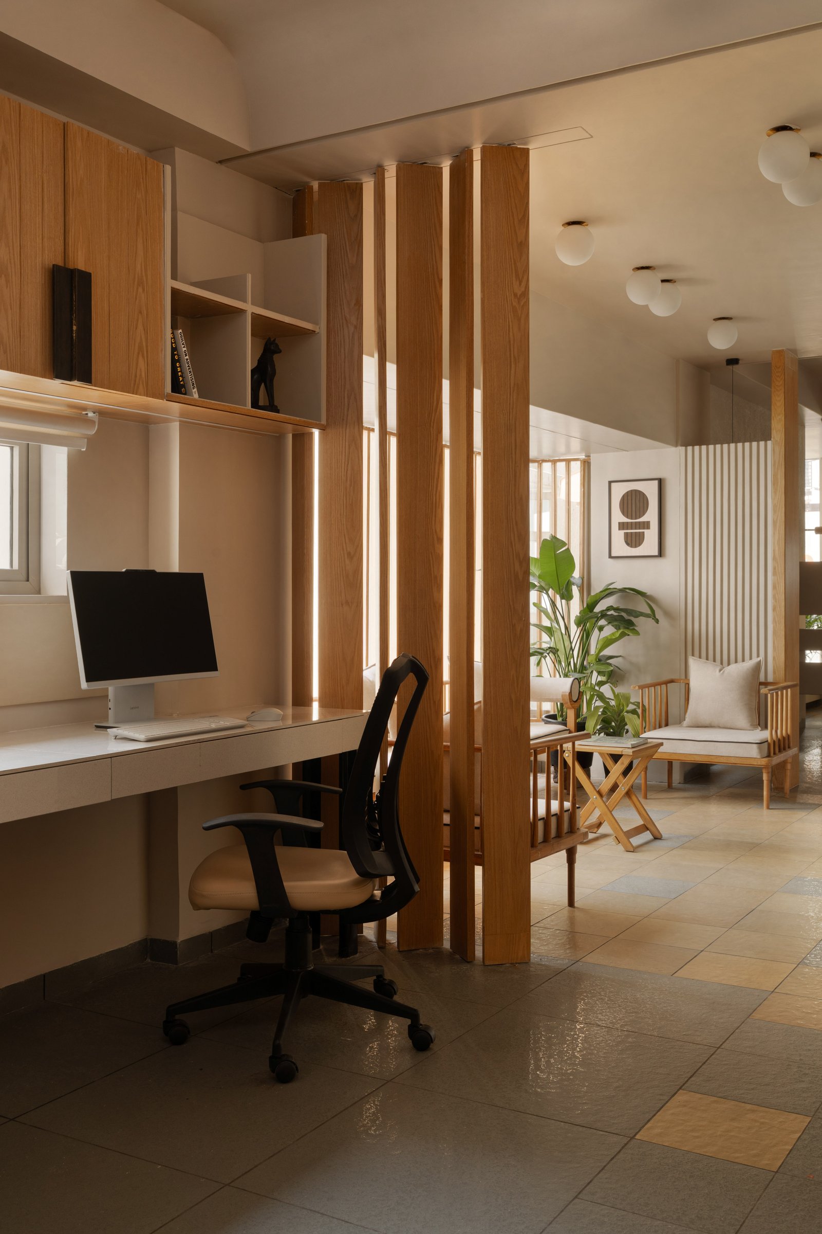 A semi-private workstation screened by vertical wood members from the reception lounge beyond