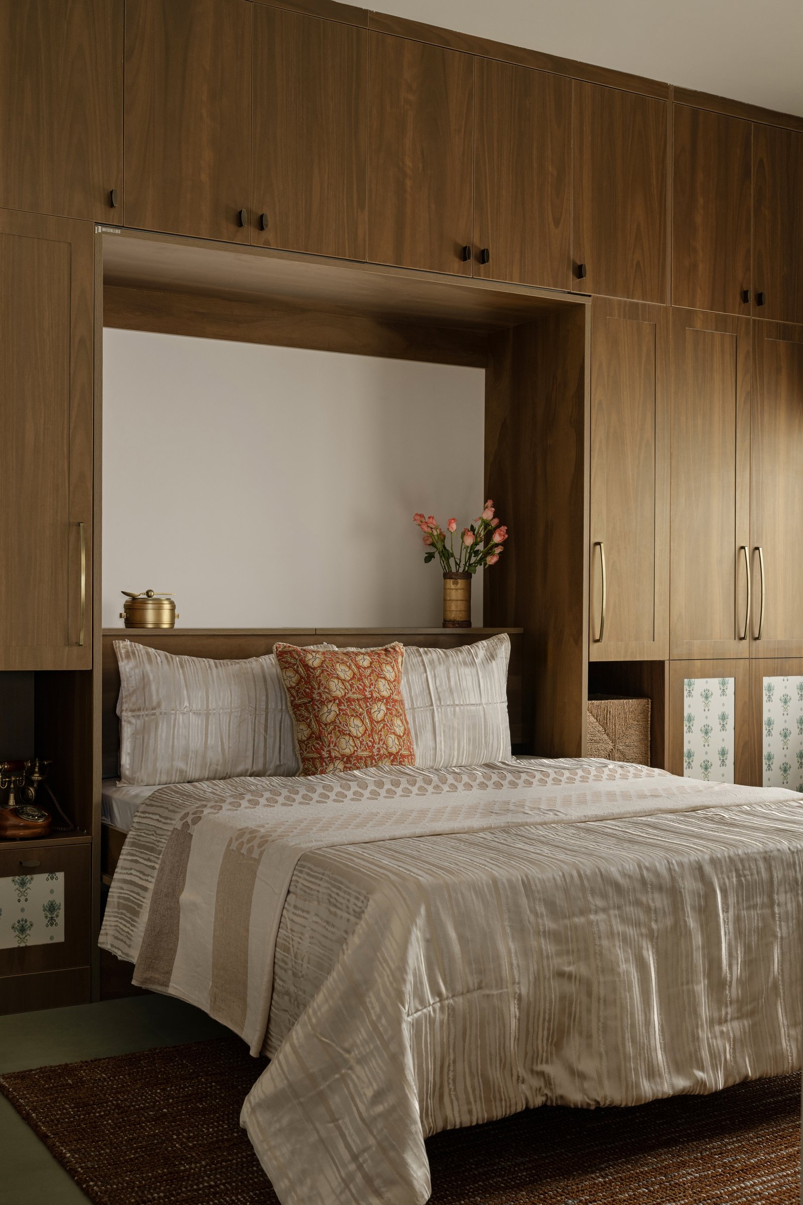 The master bedroom, where wooden wardrobes wrap a recessed niche above the headboard
