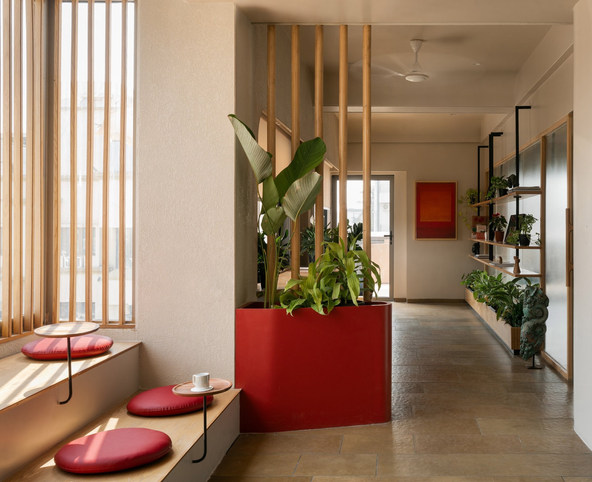 The transition corridor, with a built-in window bench, a terracotta planter and a long shelving system along the opposite wall
