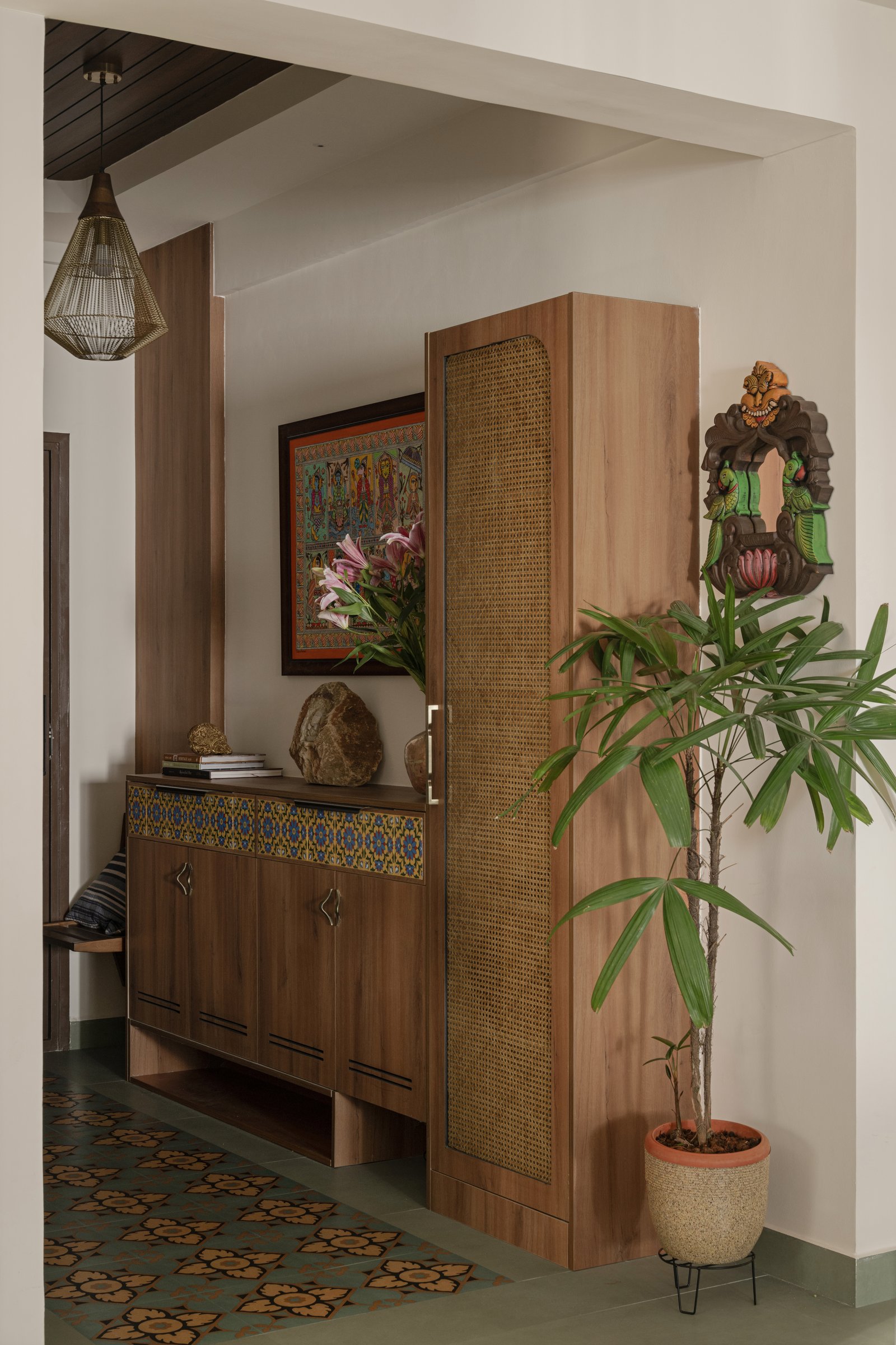 The foyer, where encaustic tiles and a cane-fronted cabinet set the home's material grammar before a single room has been entered