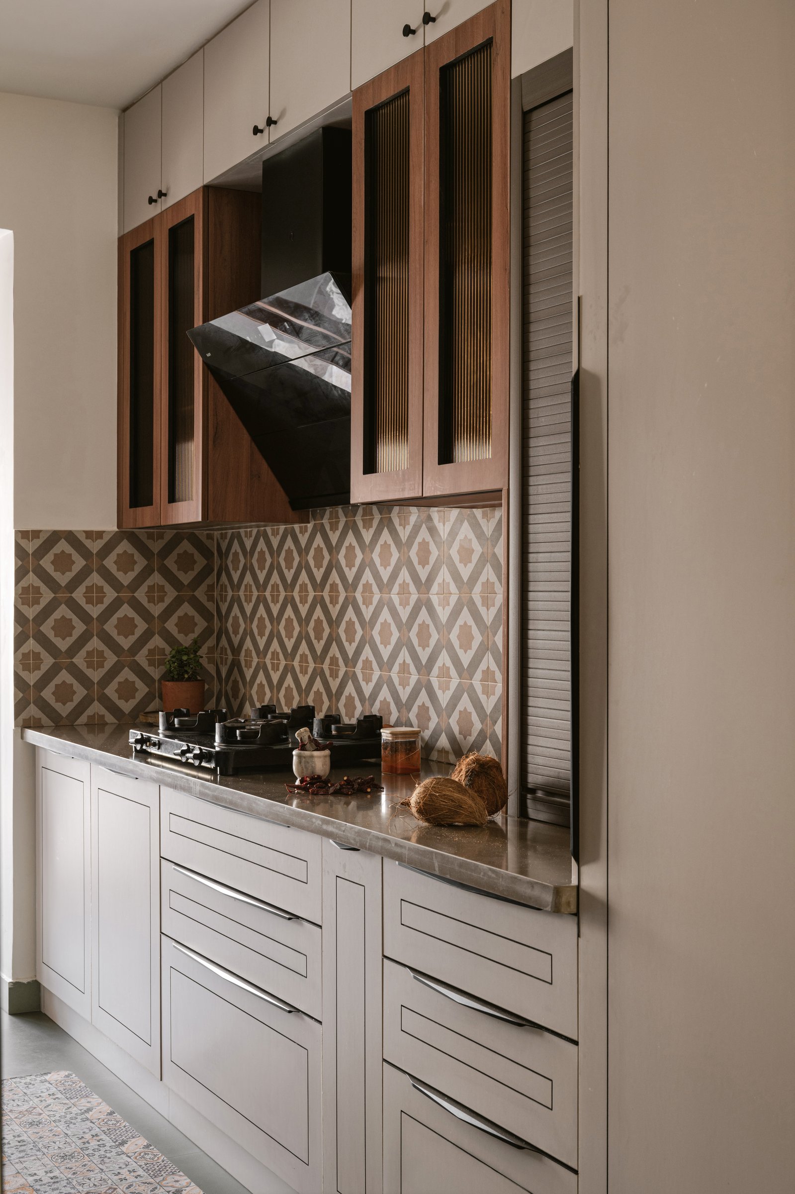 The kitchen's appliance run: a built-in oven column and roller-shuttered storage keep the equipment out of view