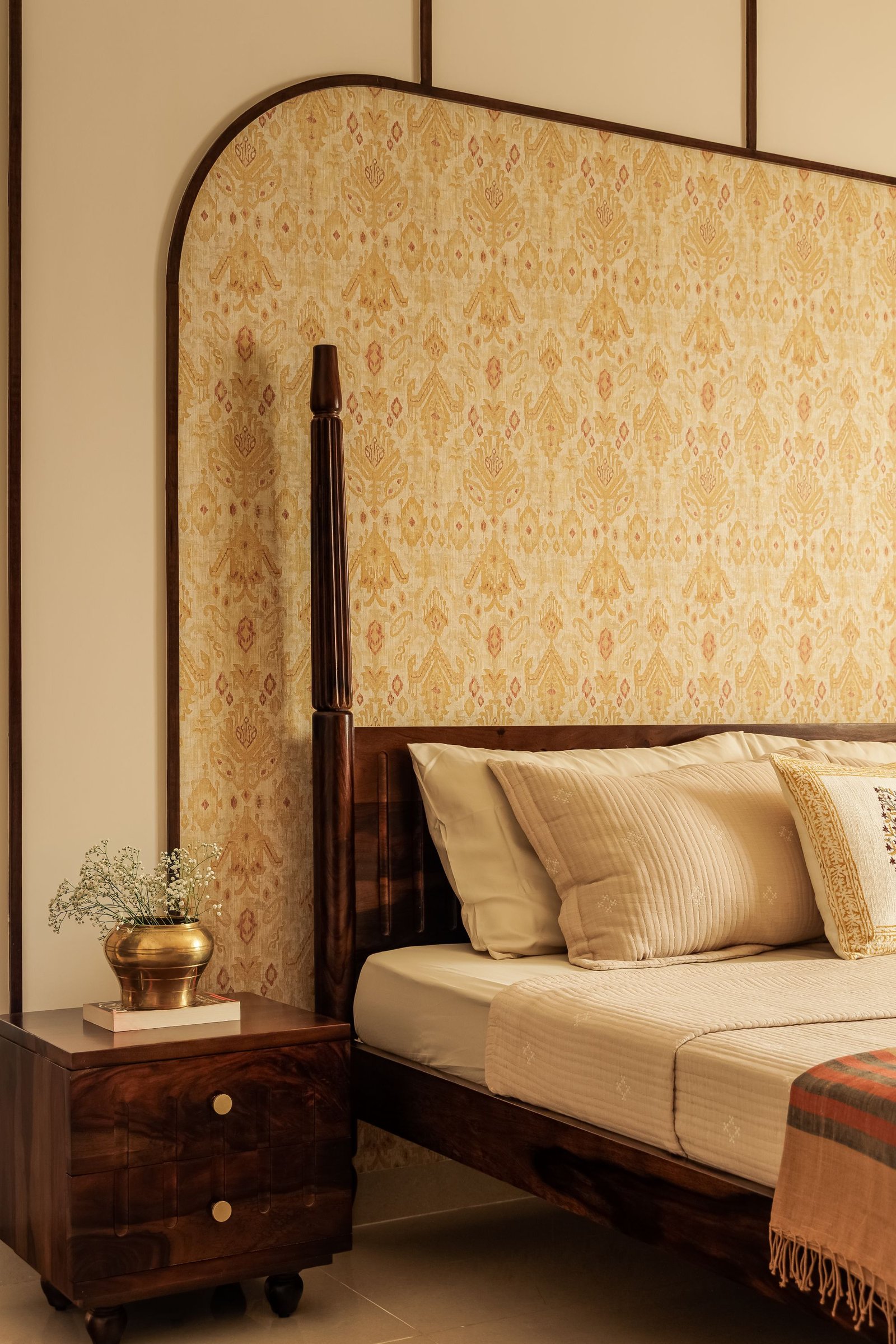 The headboard wall up close, where the patterned panel reads almost as a textile within its walnut frame