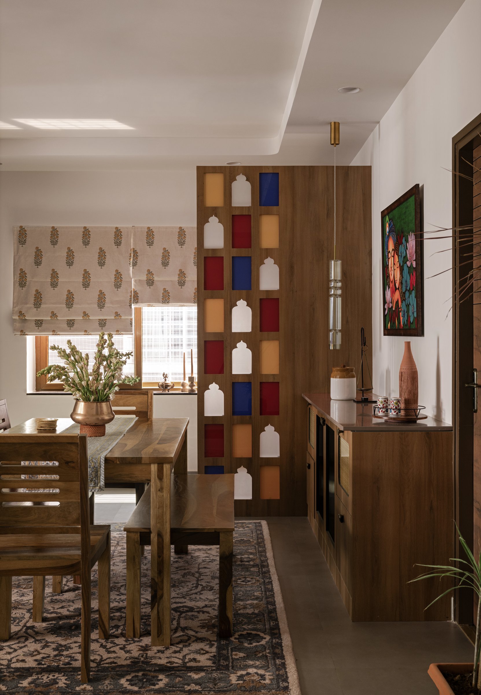 The dining zone, where a jharokha-style partition in red, yellow and blue glass filters light as colour