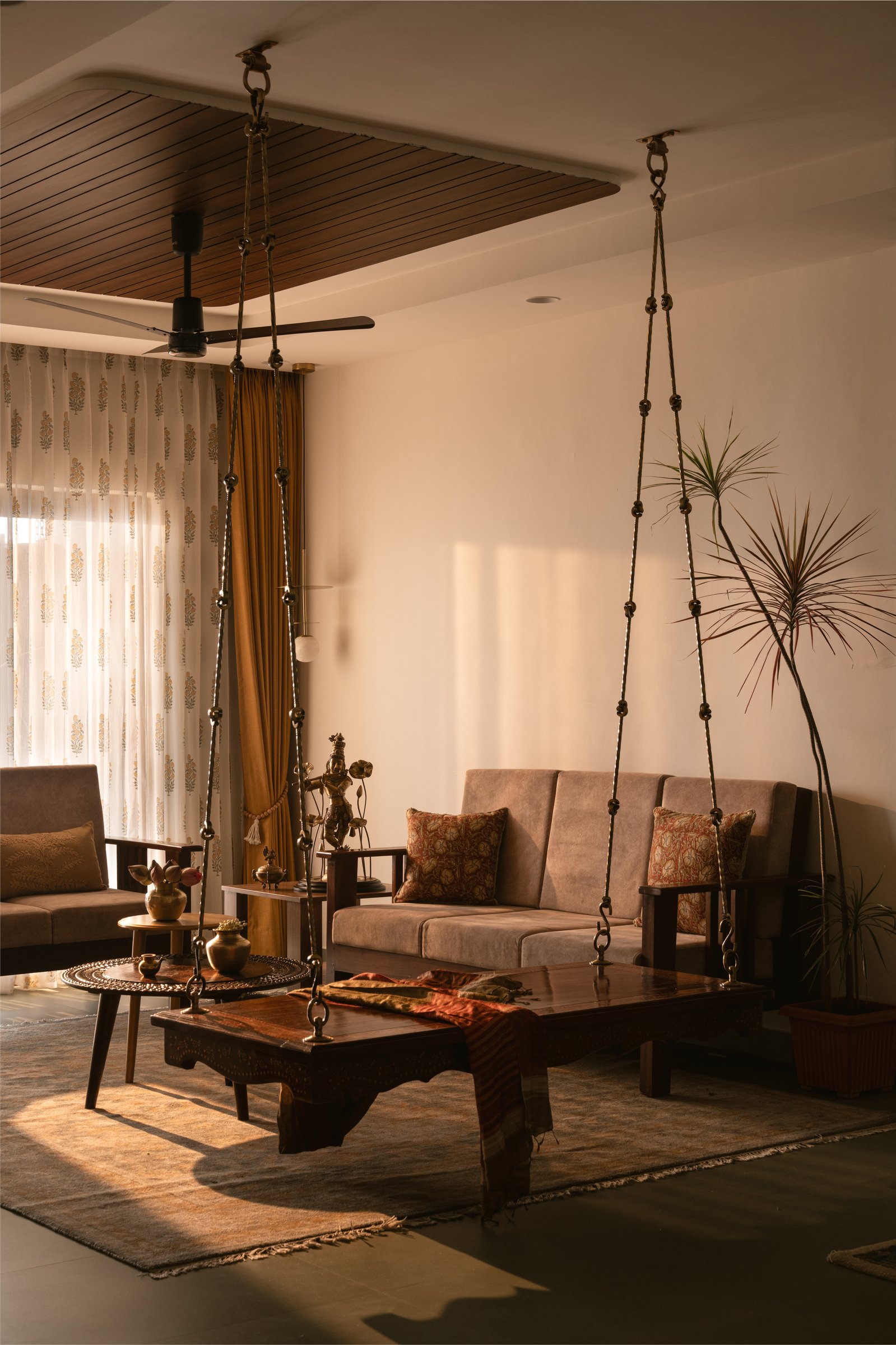 The living room, where a refurbished sofa and an antique jhoola in brass-beaded chains share the same low, honeyed light