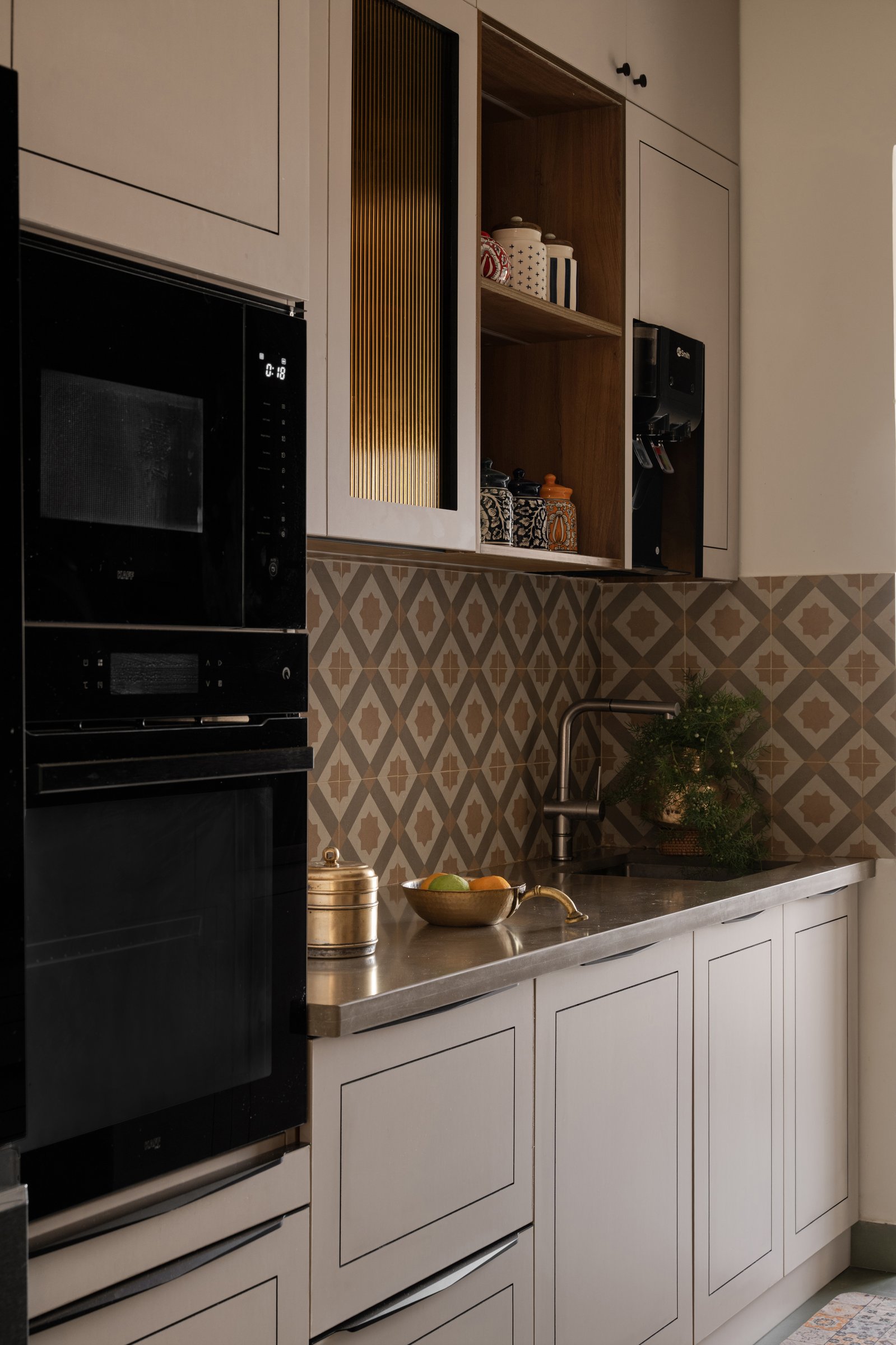 The kitchen's working wall, where geometric backsplash tile and open wooden shelving give the cabinetry its hierarchy
