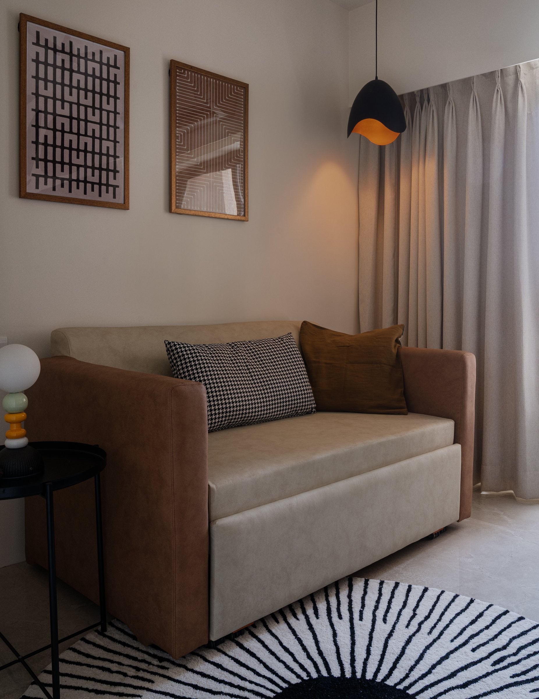 The guest room, where a leather-and-cream sofa-bed sits beneath a pair of framed graphic prints