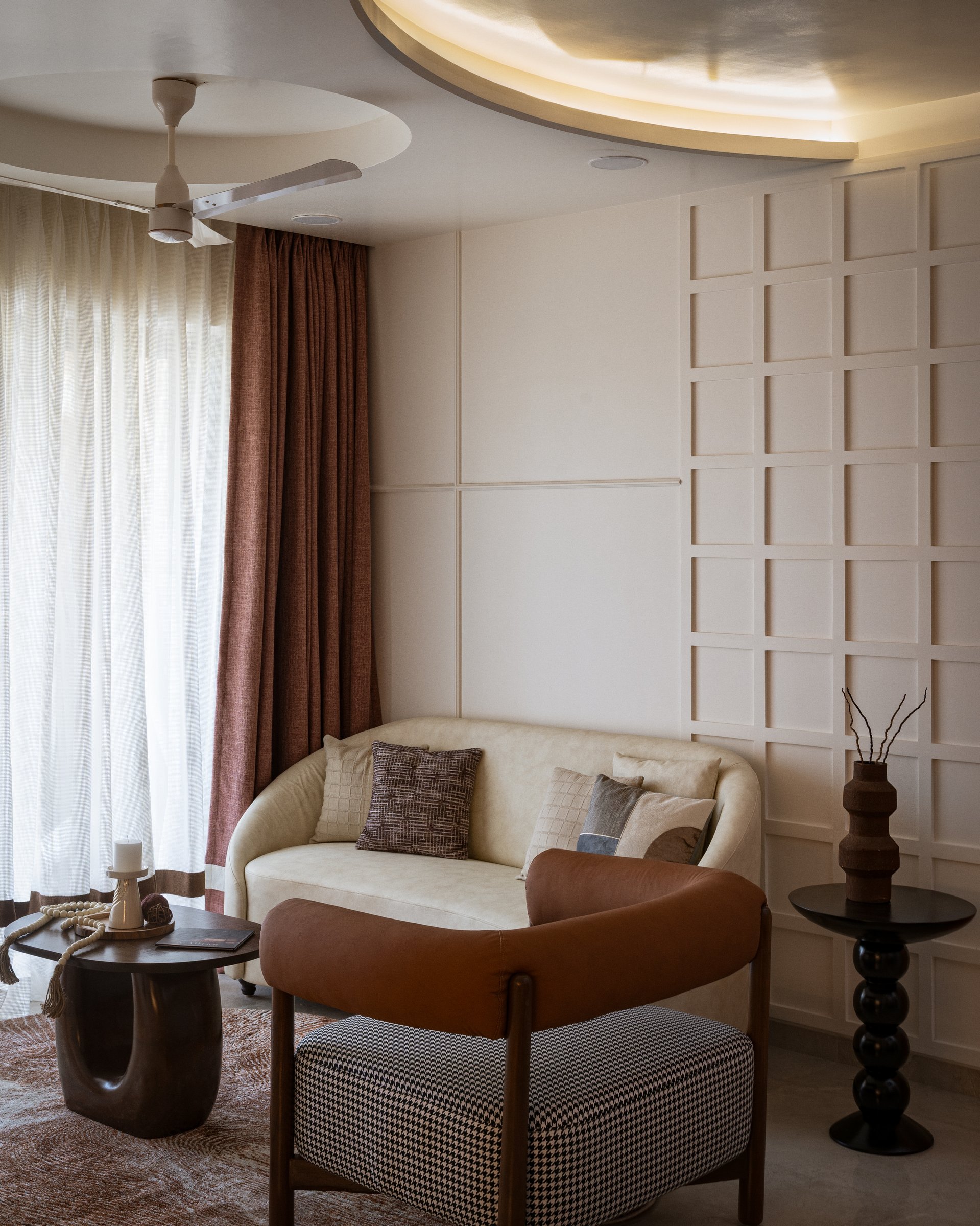 The living room, where a curved cove-lit ceiling and a grid of raised panel moulding establish the home's composed key