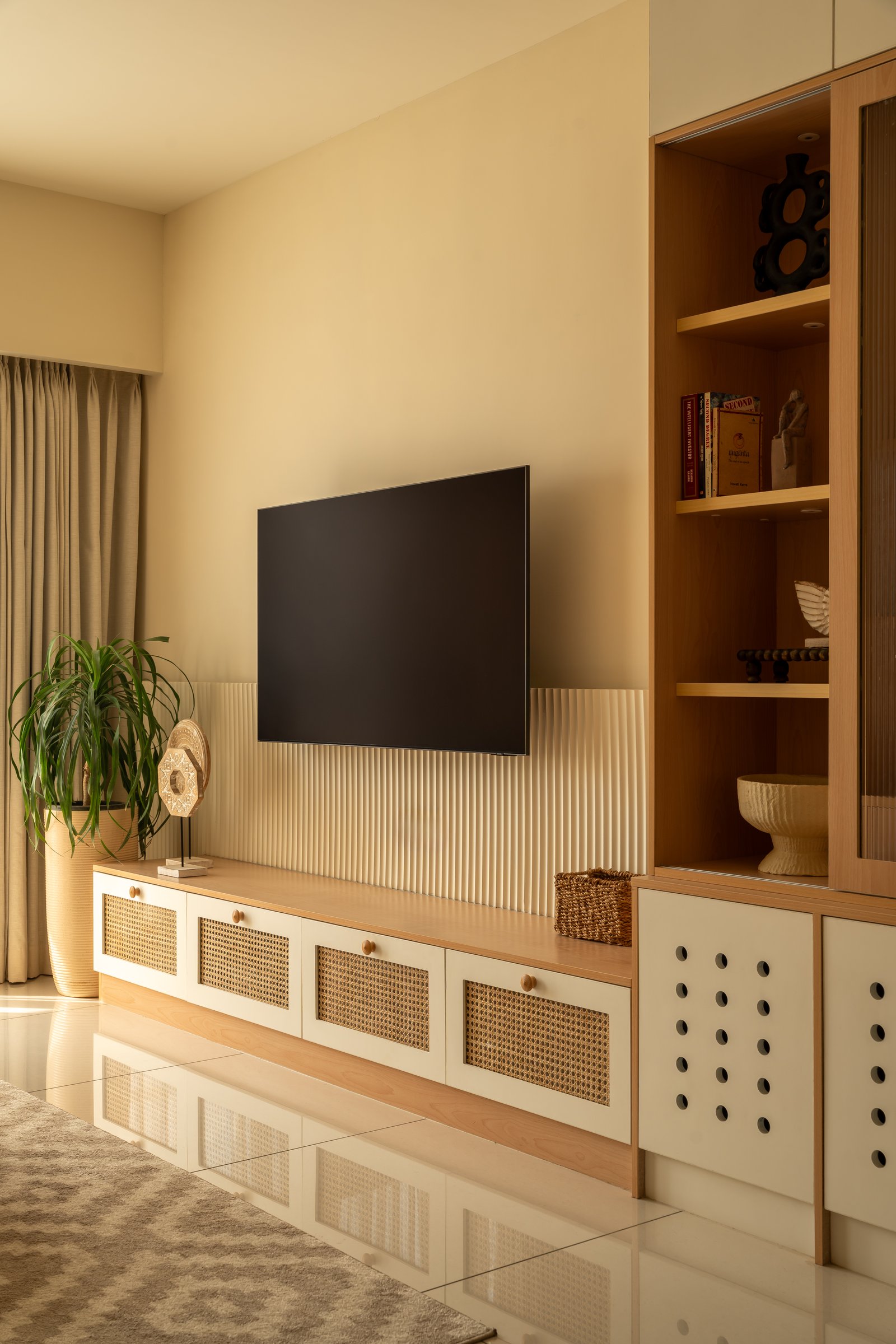 The media wall, with cane-front drawers and a reeded panel behind the television lending rhythm to a long horizontal run