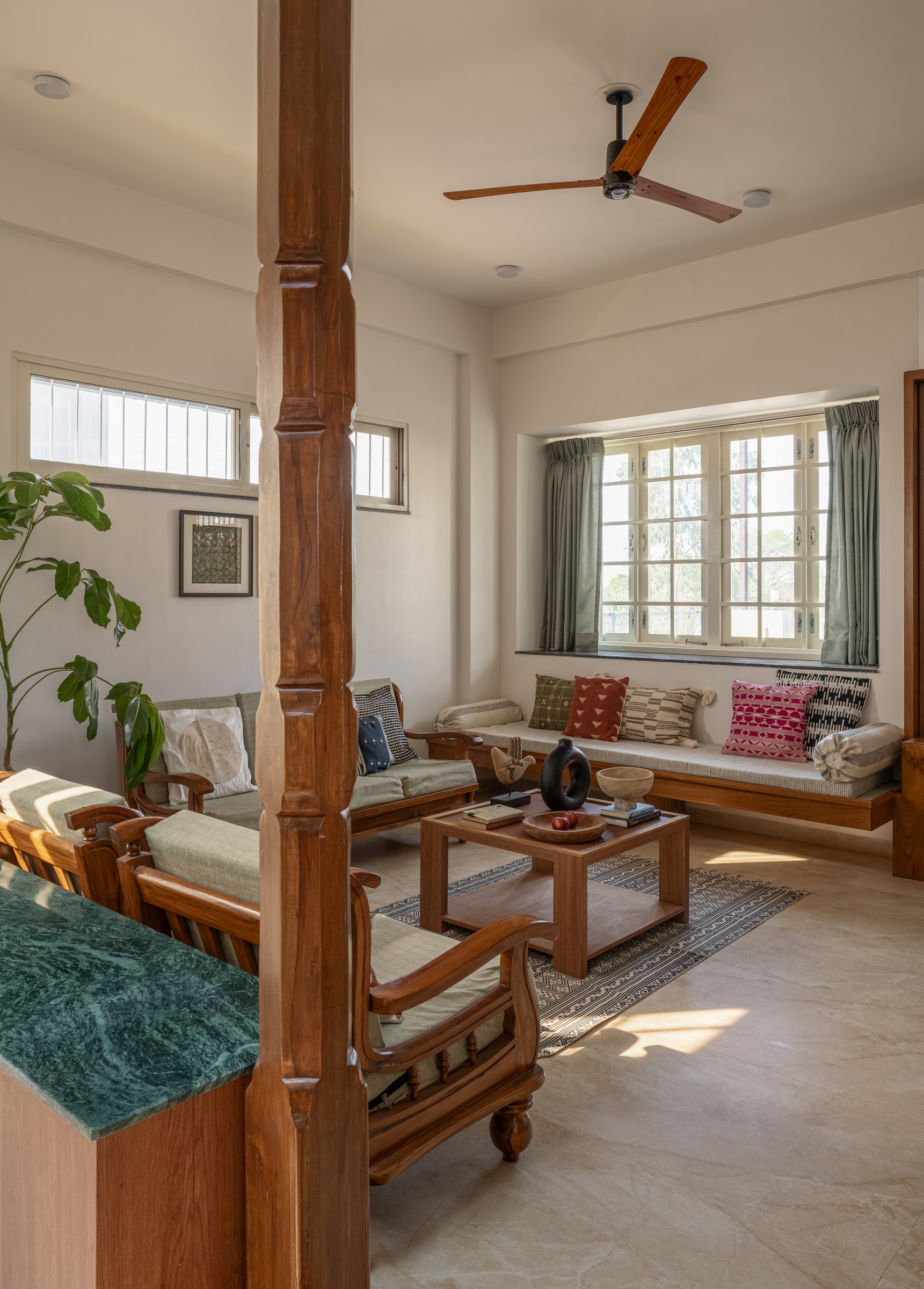 The window seat under the deep mullioned window, where the room's only saturated colours are quietly gathered