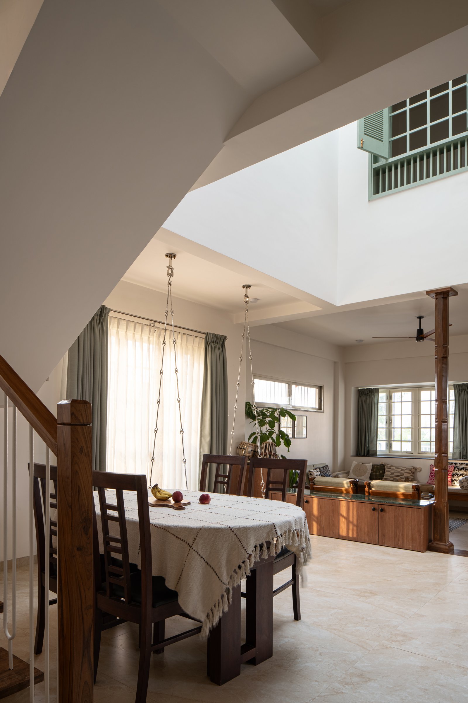 The dining area sits directly beneath the skylight, with the swing hovering beside it and a mint-green louvred window watching from above