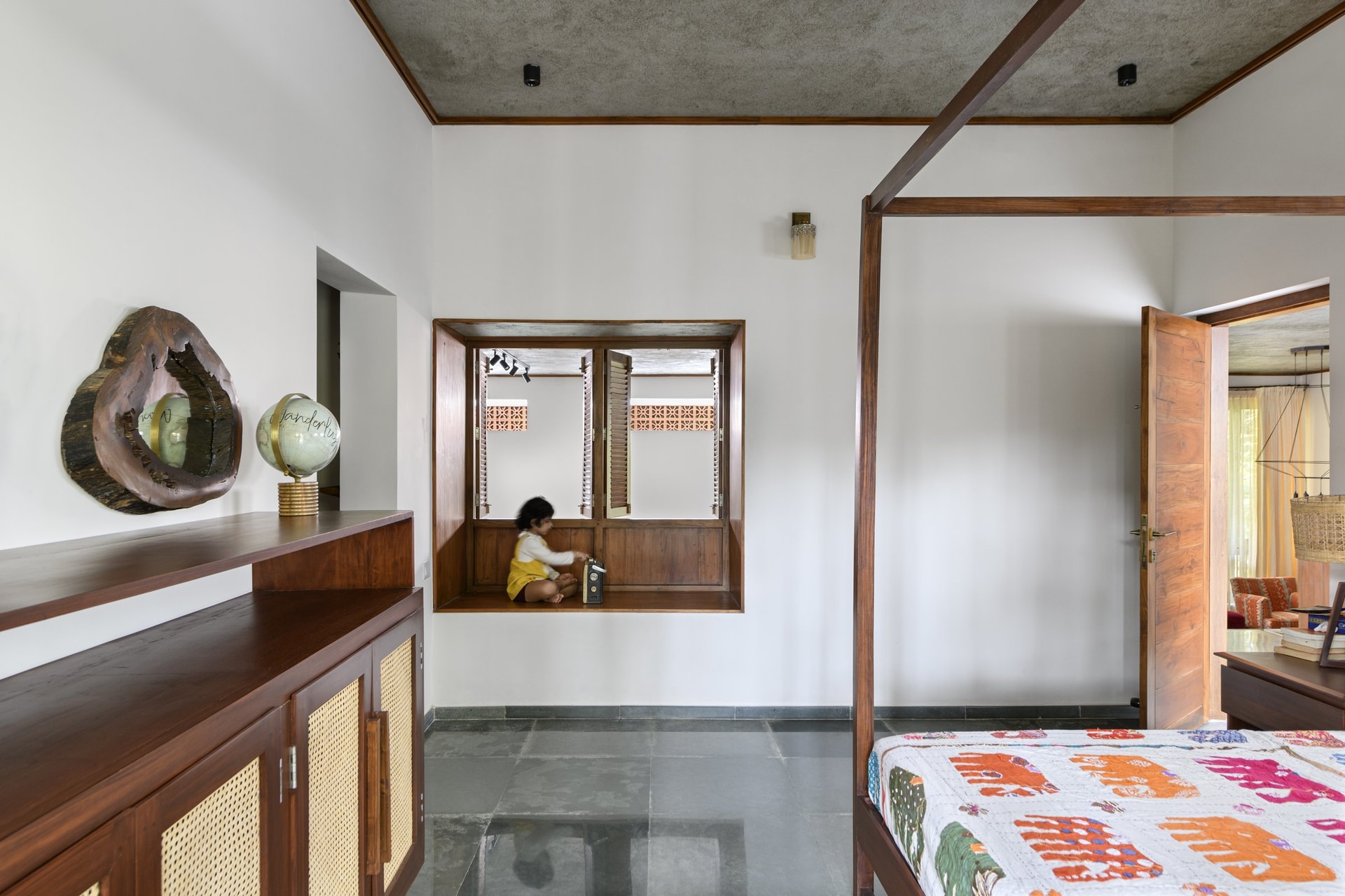 A built-in window seat lined in timber, framed by louvered shutters opening onto the brick screen outside