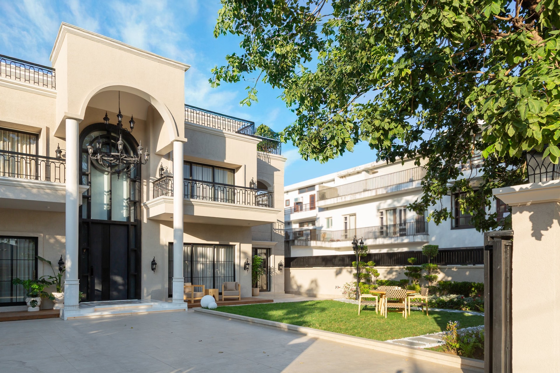 The villa's exterior: a tall central arch frames the entrance, flanked by slim fluted columns and the mature tree that shaped the home's view corridors