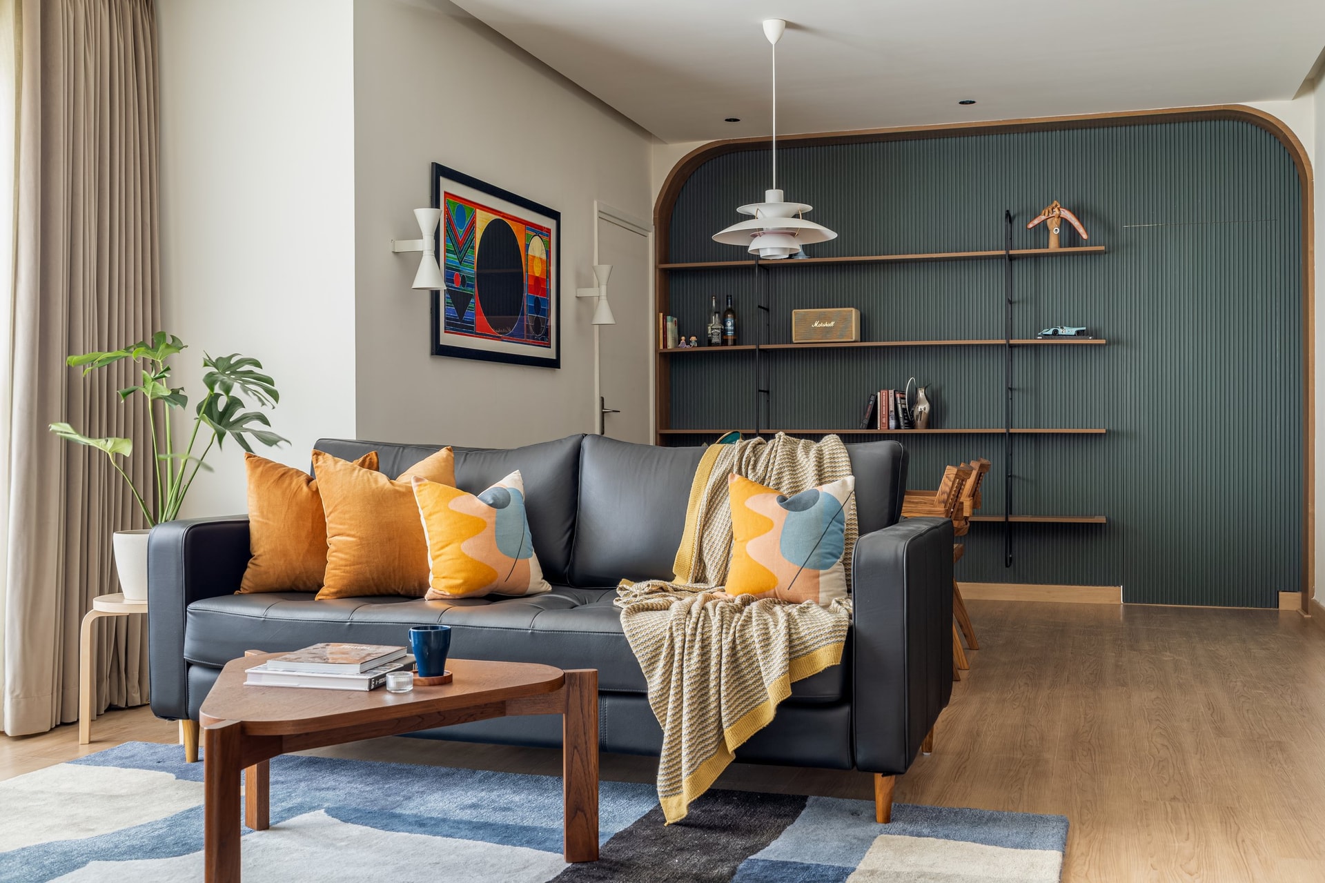 The living room: a deep navy leather sofa against the olive fluted wall, with arched detailing that reappears throughout the home