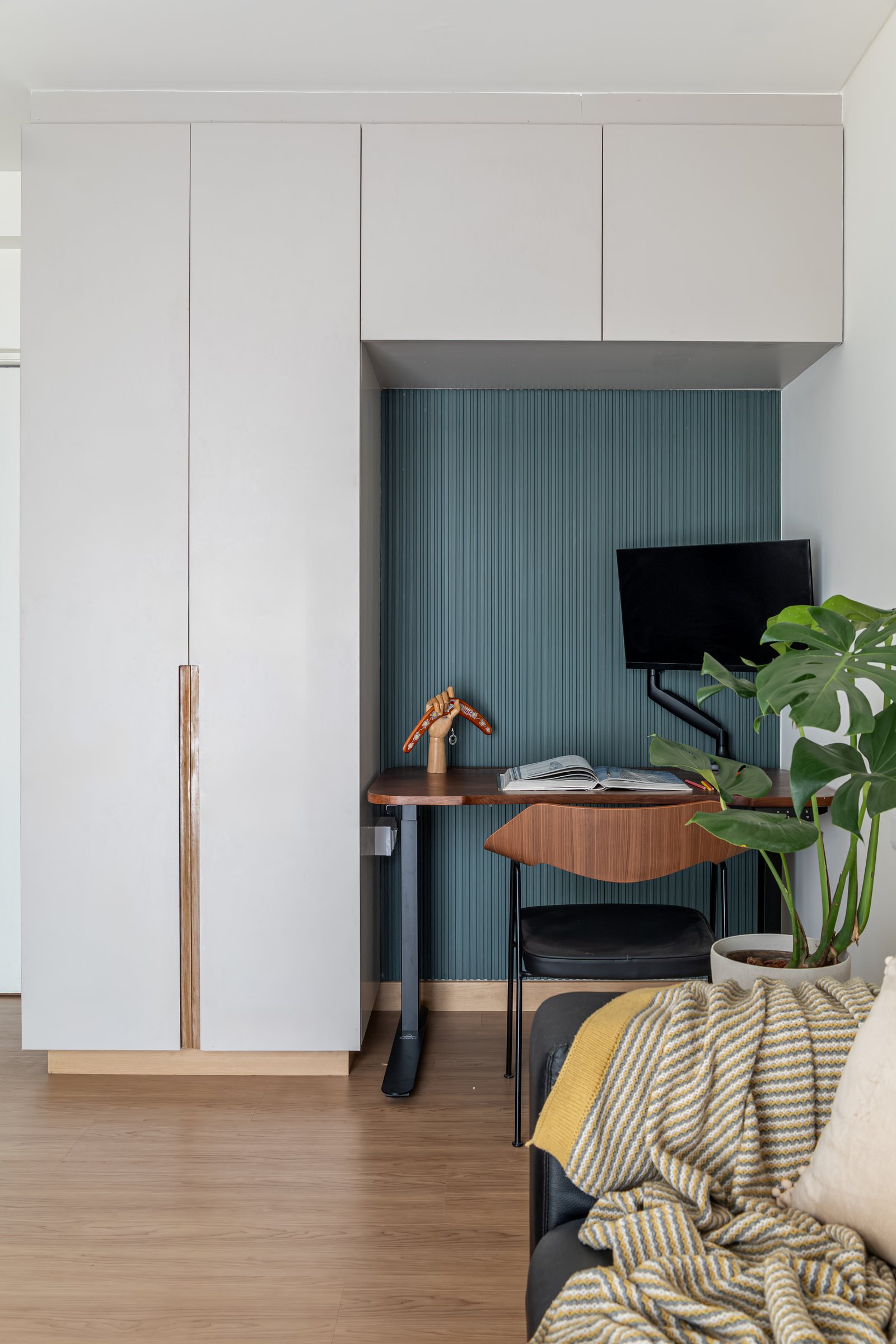 The work nook recessed into olive fluting, with a walnut desk and personal objects anchoring the corner