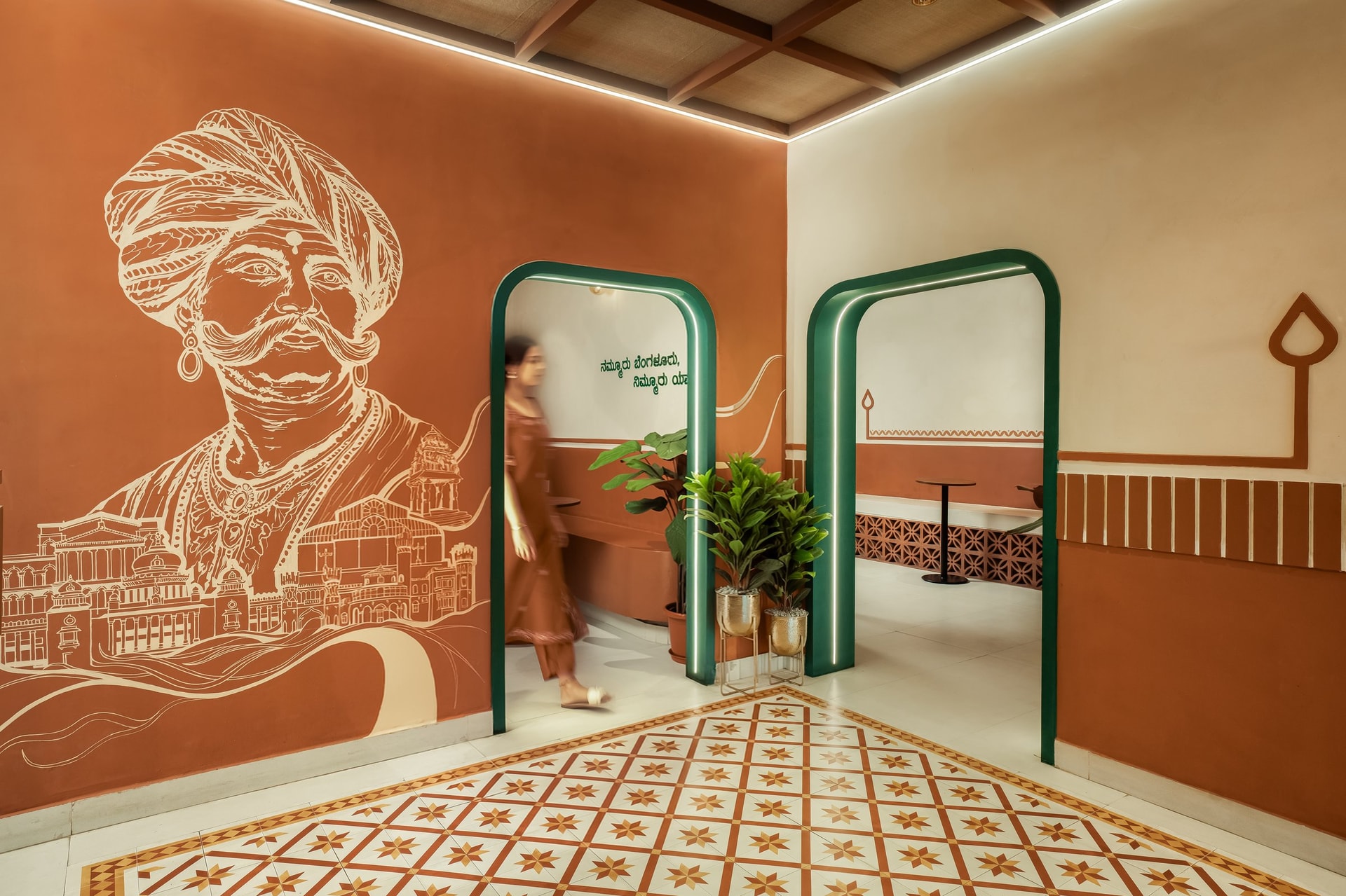 The foyer mural of Kempegowda, with green-arched portals leading into the dining halls and the patterned cement tile floor below