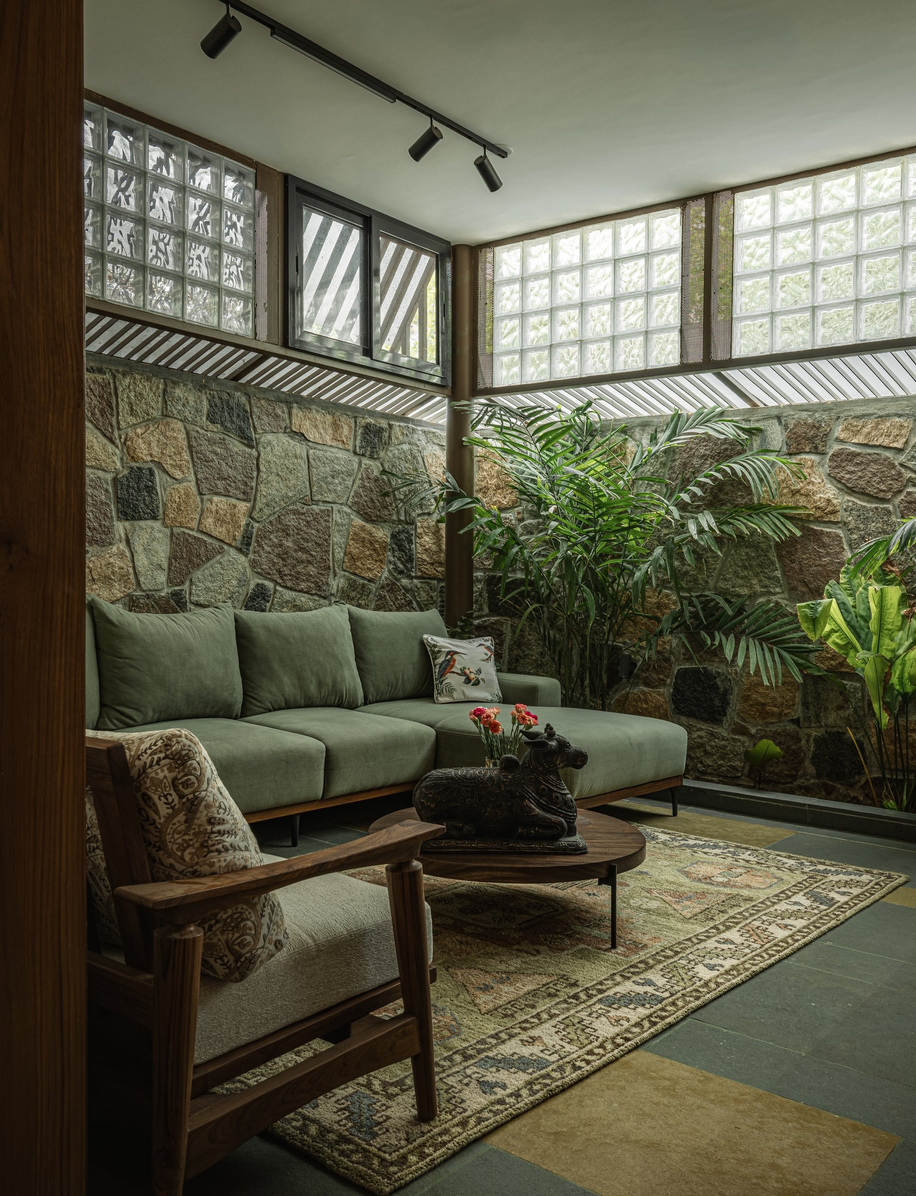 A second view of the living room, where stone, glass block and perforated metal stack into a single legible section