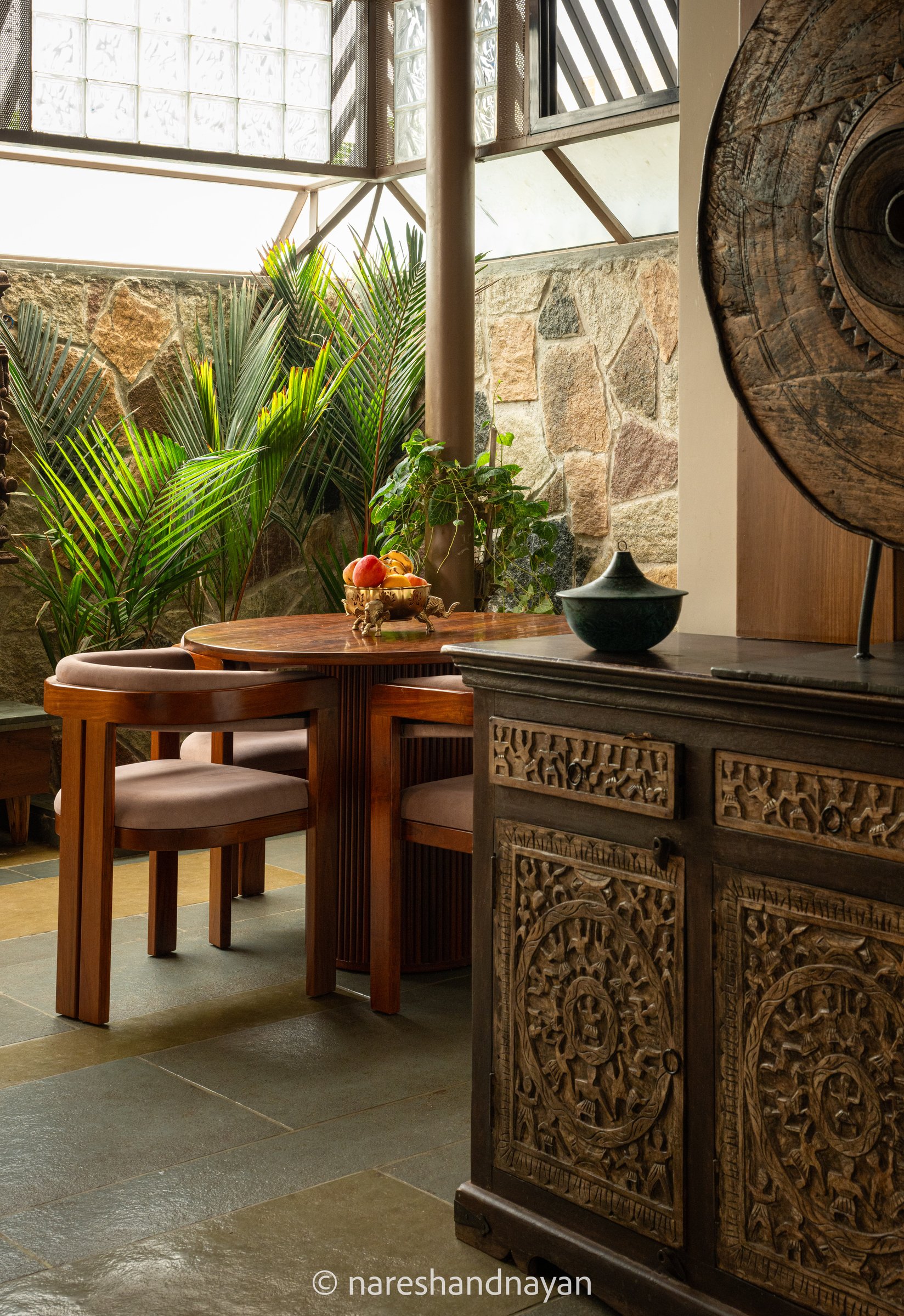 The dining nook itself, set against a planted edge of palm and rubble stone