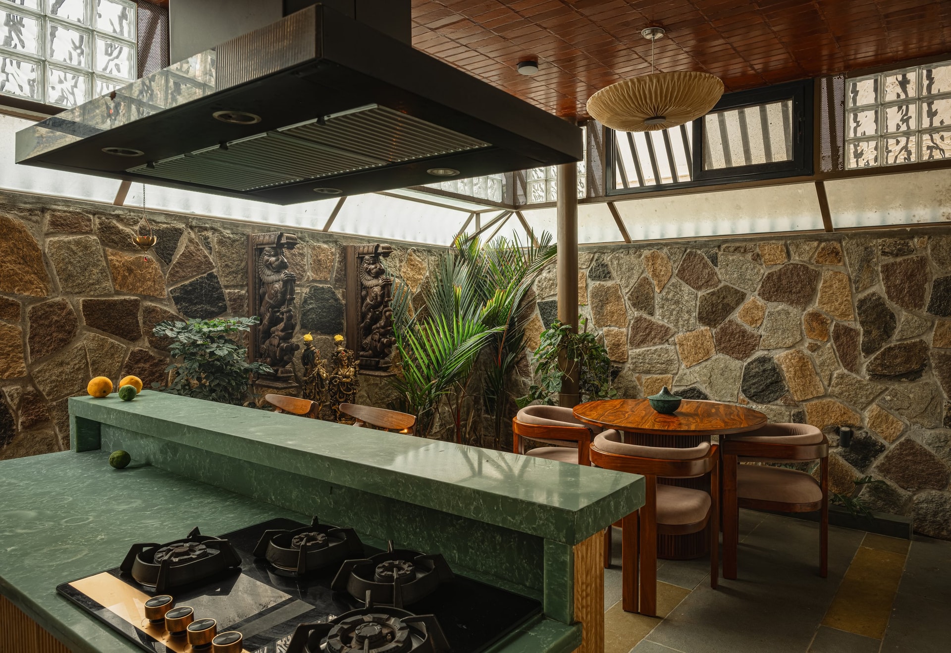 The kitchen-dining volume, where a long green stone counter, terracotta filler-slab ceiling and rubble wall hold the room together