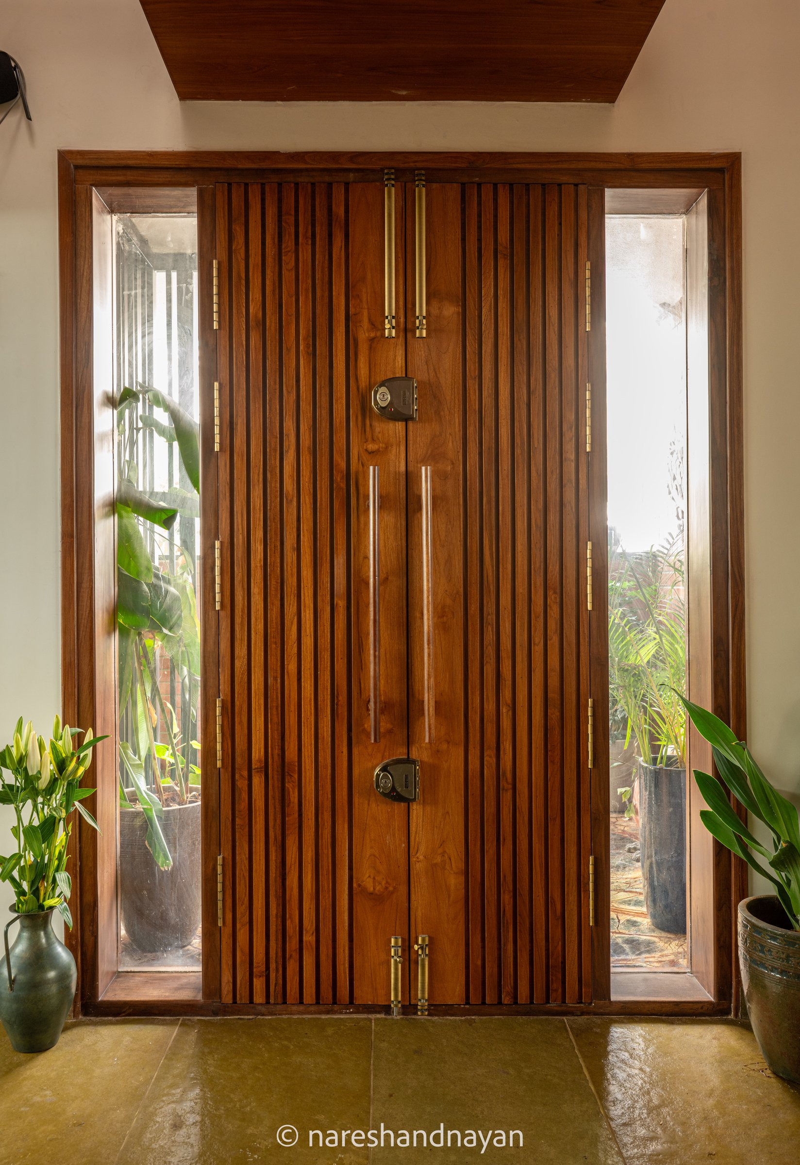The front door, slatted hardwood between glazed side panels, sets the tone before the home opens
