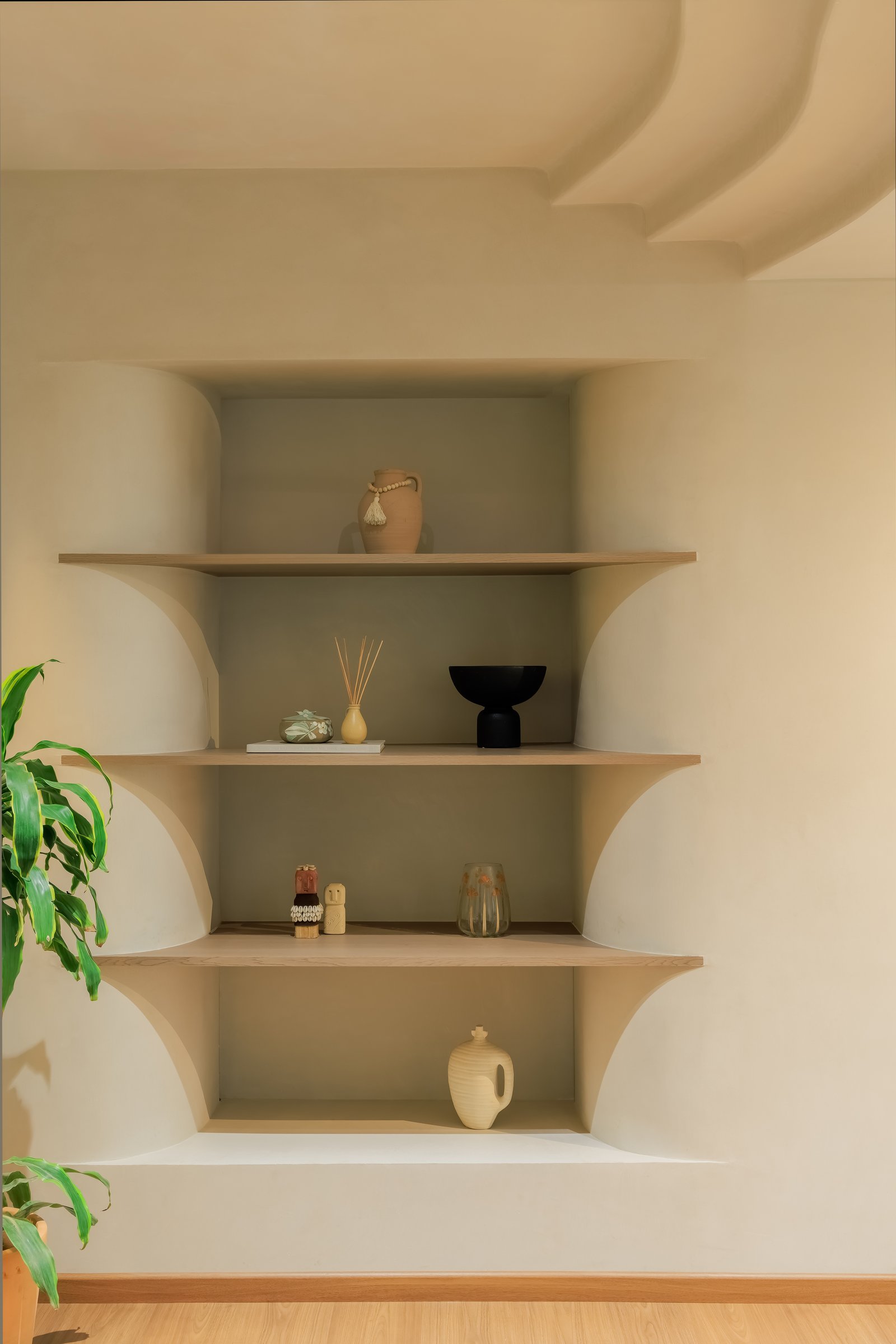 A built-in niche holds terracotta and ceramic objects beneath a sculpted plaster ceiling