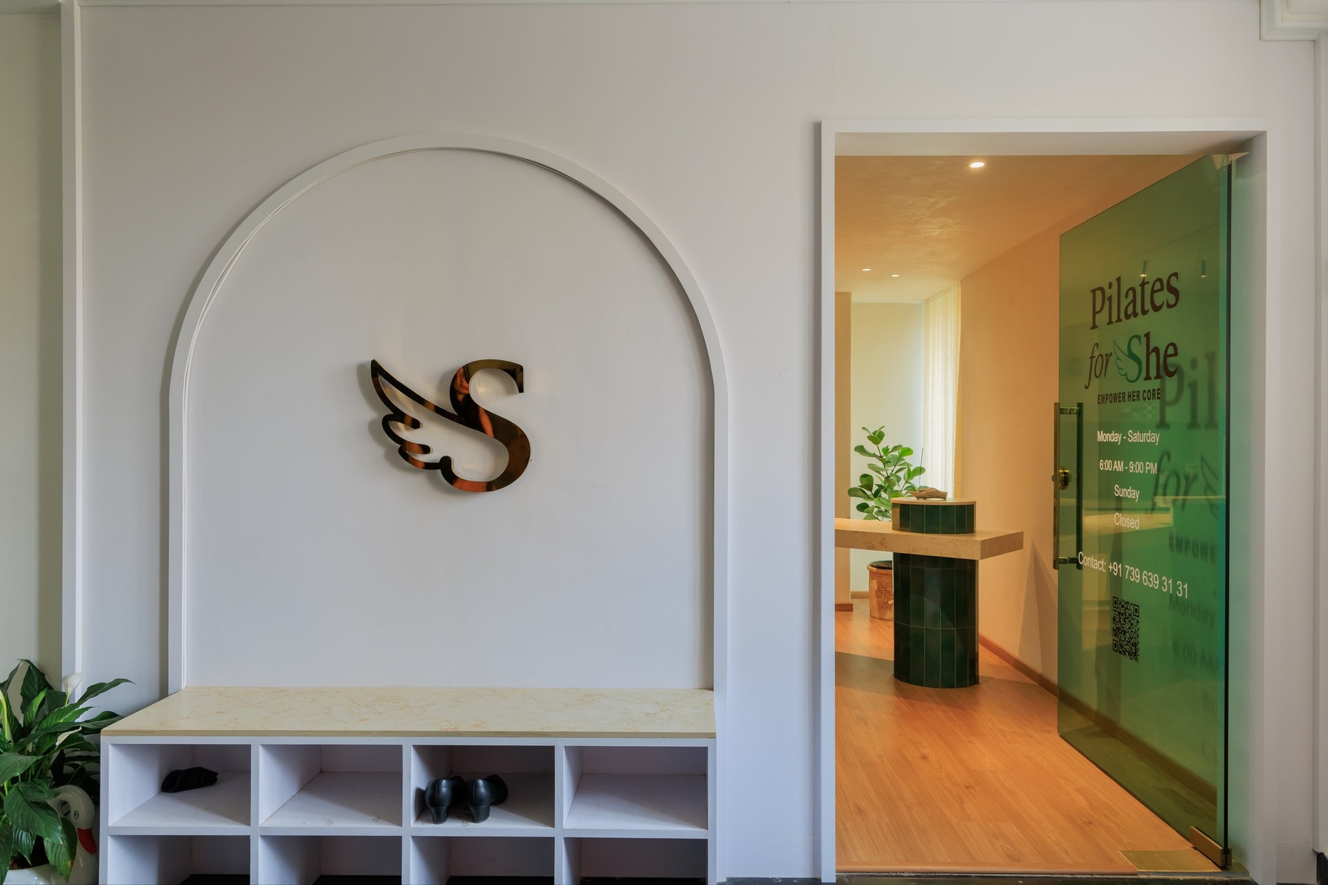 The entry alcove: a low bench, shoe cubbies, and the winged-S emblem set the tone of arrival