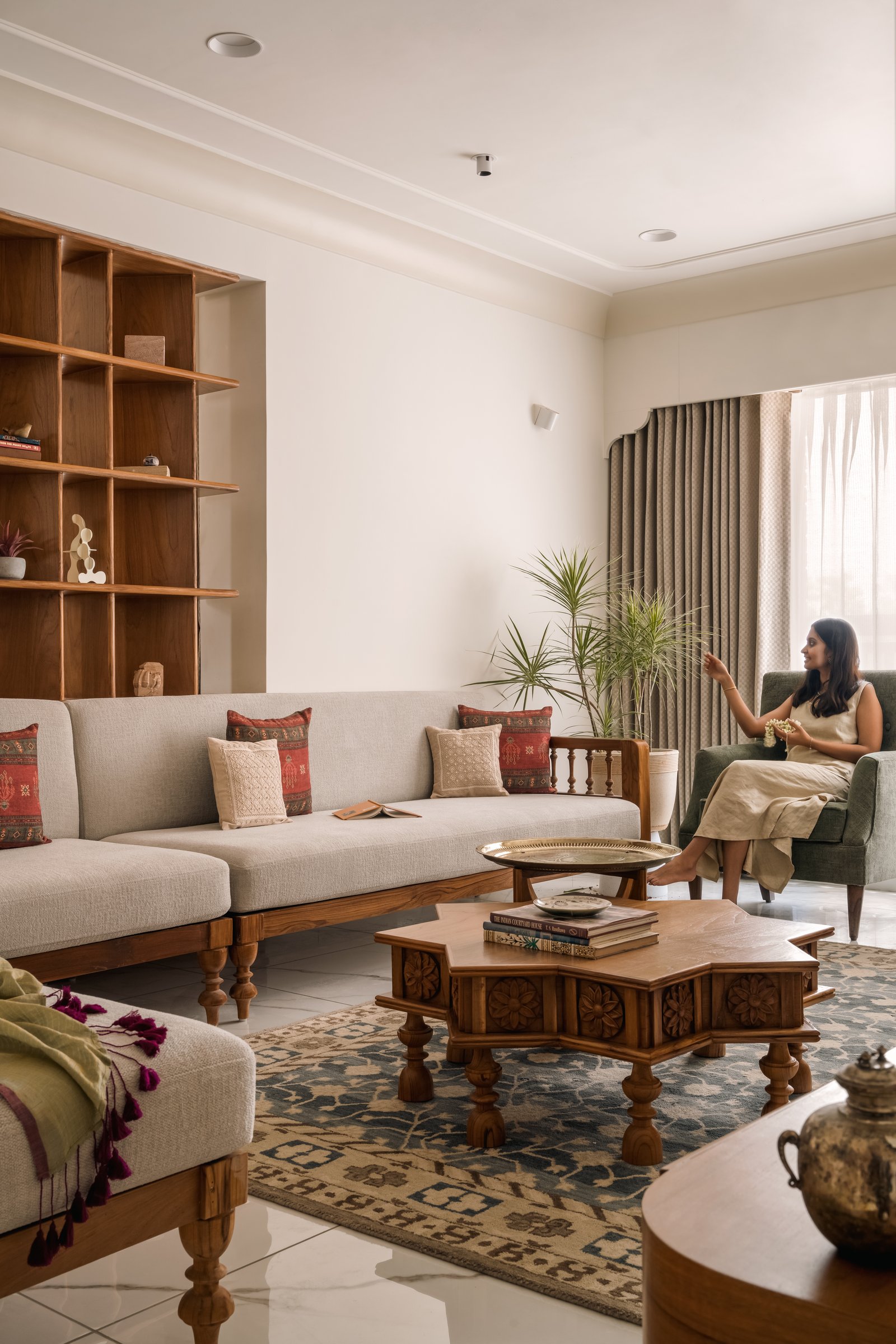 The living room from a wider vantage, where open wood shelving anchors the seating composition