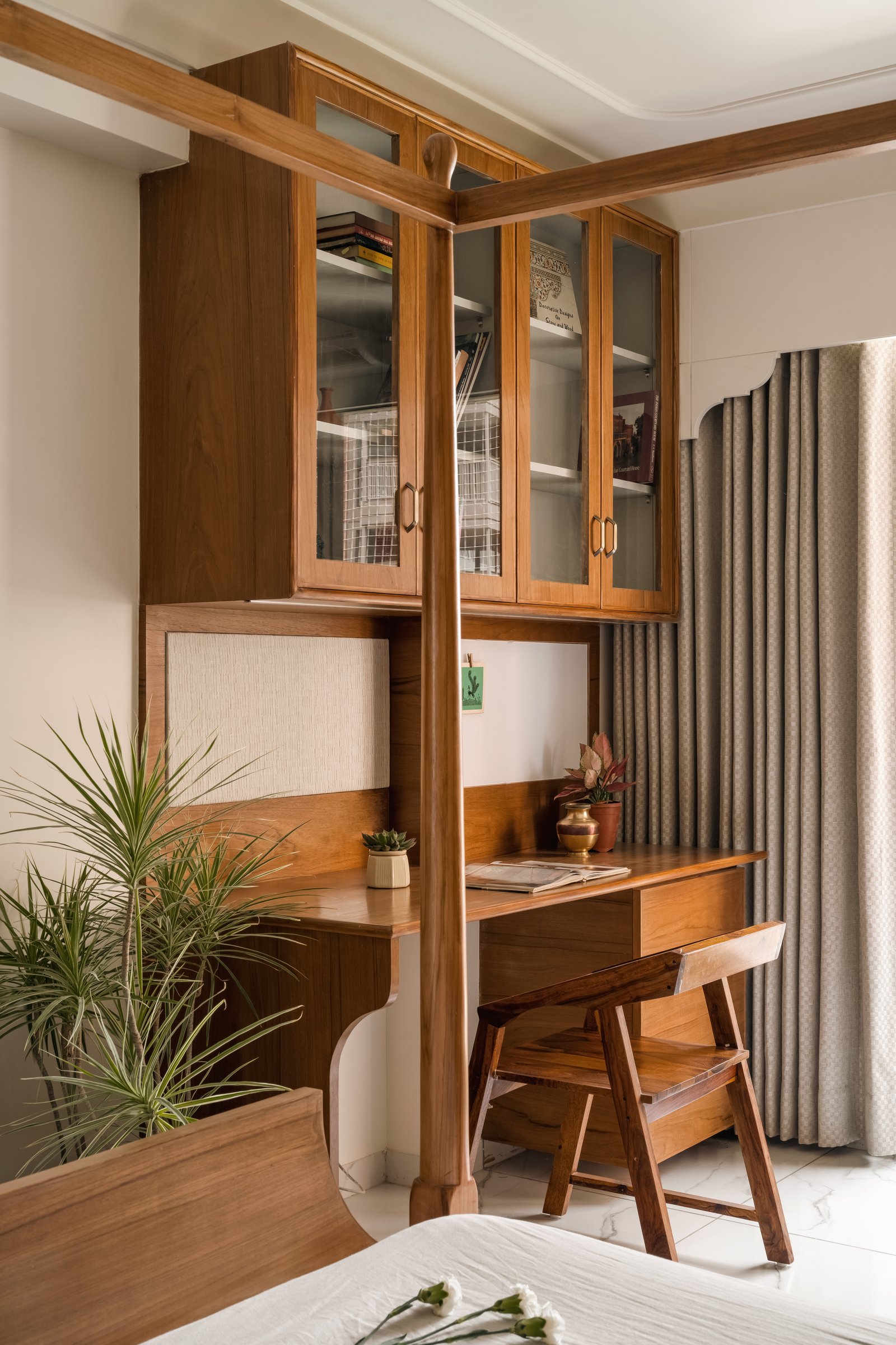 The bedroom’s built-in desk, where a glass-fronted cabinet and slatted chair fold a workspace into the room