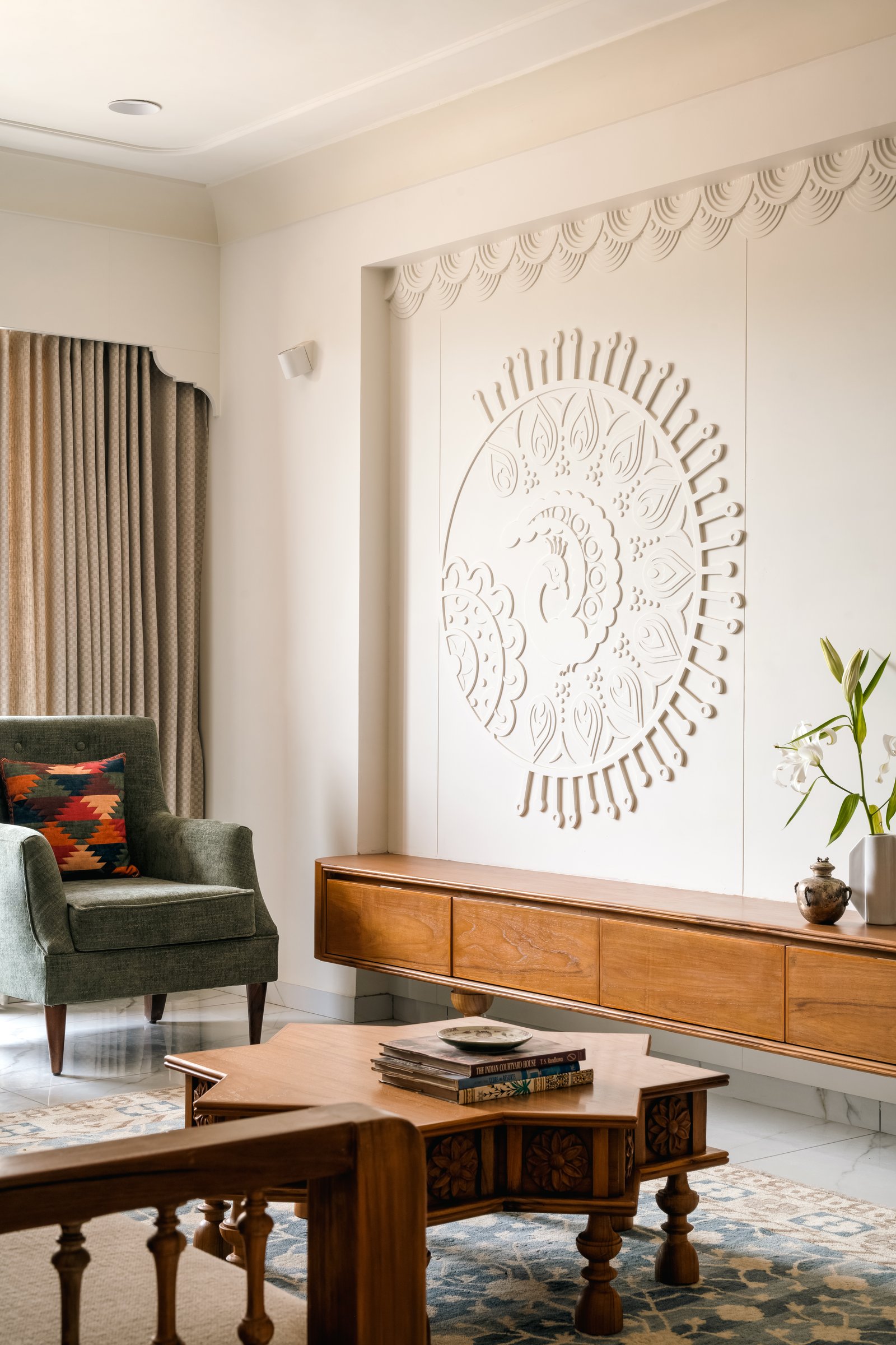 The mural wall, where a Gond-inspired motif is rendered in monochromatic plaster relief above a floating wood console