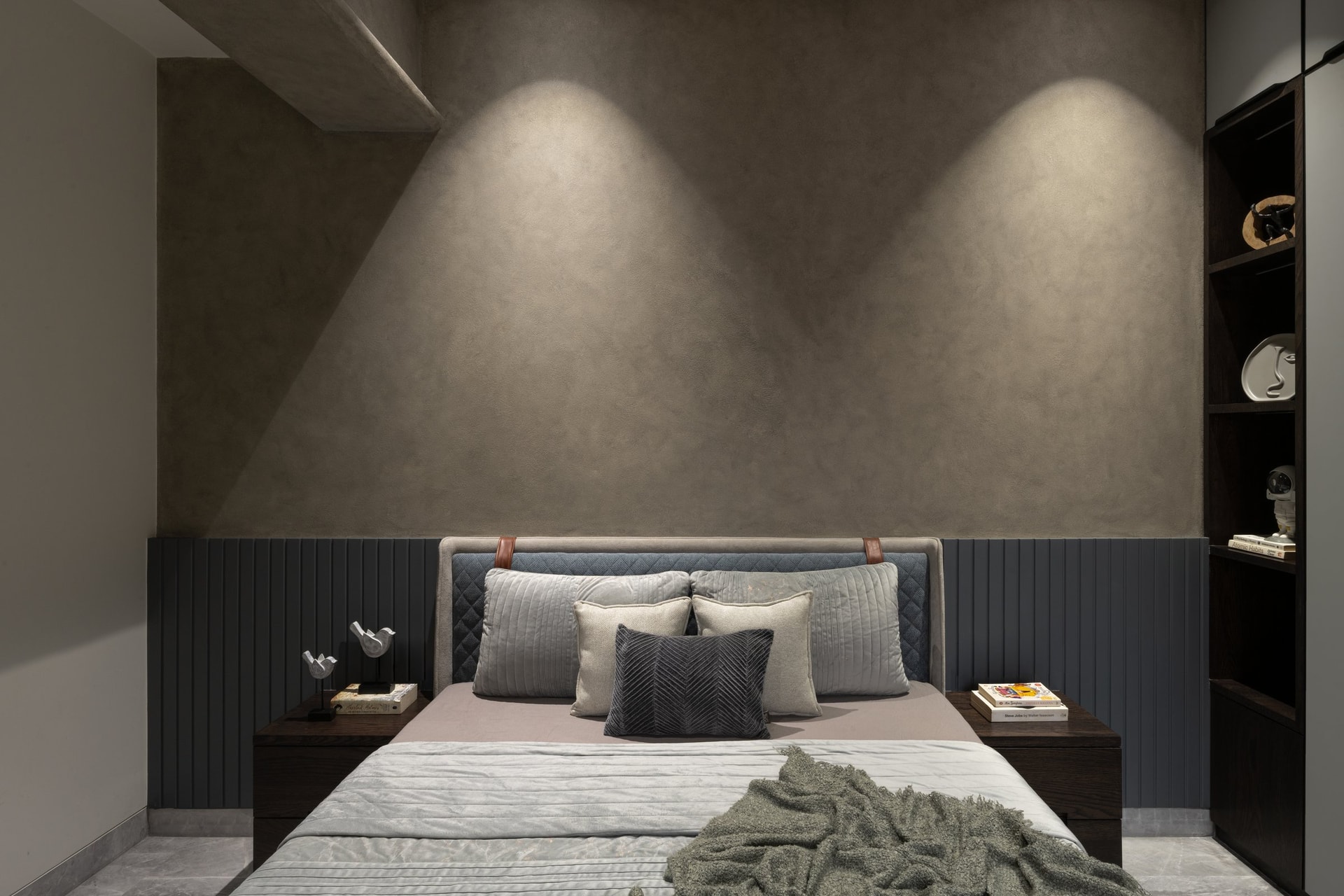 The son's bedroom commits to an exposed-materials thought: textured grey plaster washed by two cones of light