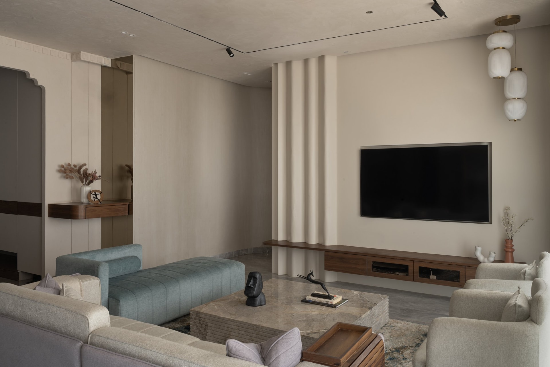 The TV wall's fluted plaster column cascades from ceiling to floor, softening the room's geometry