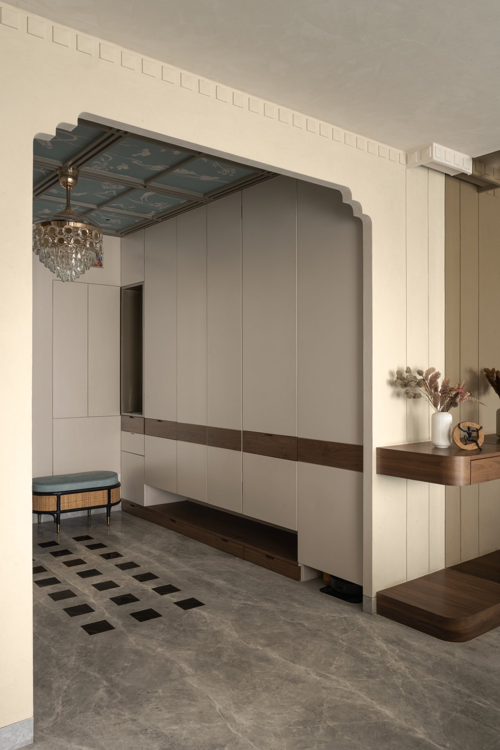 The foyer's scalloped portal frames concealed storage; the patterned marble floor draws the eye inward