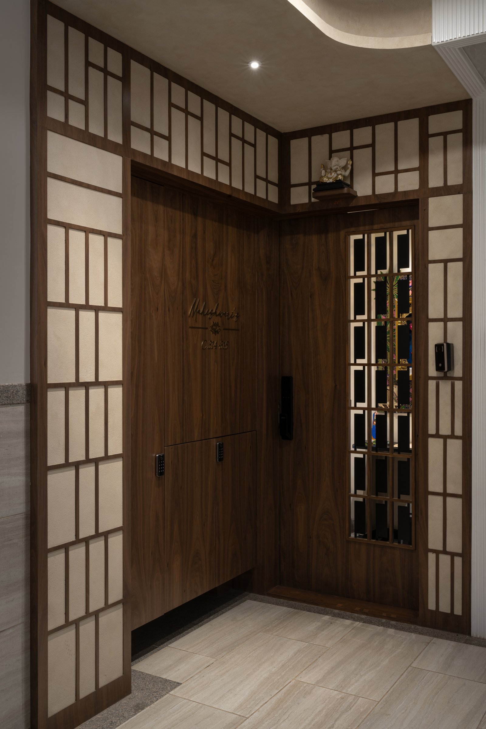 The entry threshold: a walnut-panelled door inset with fabric panels and a glimpse of the temple within