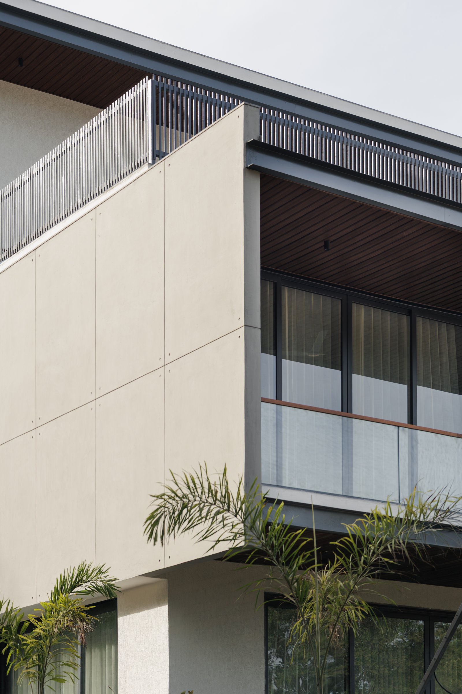 A corner detail, stucco meeting slatted metal balustrade above and a timber-lined soffit below