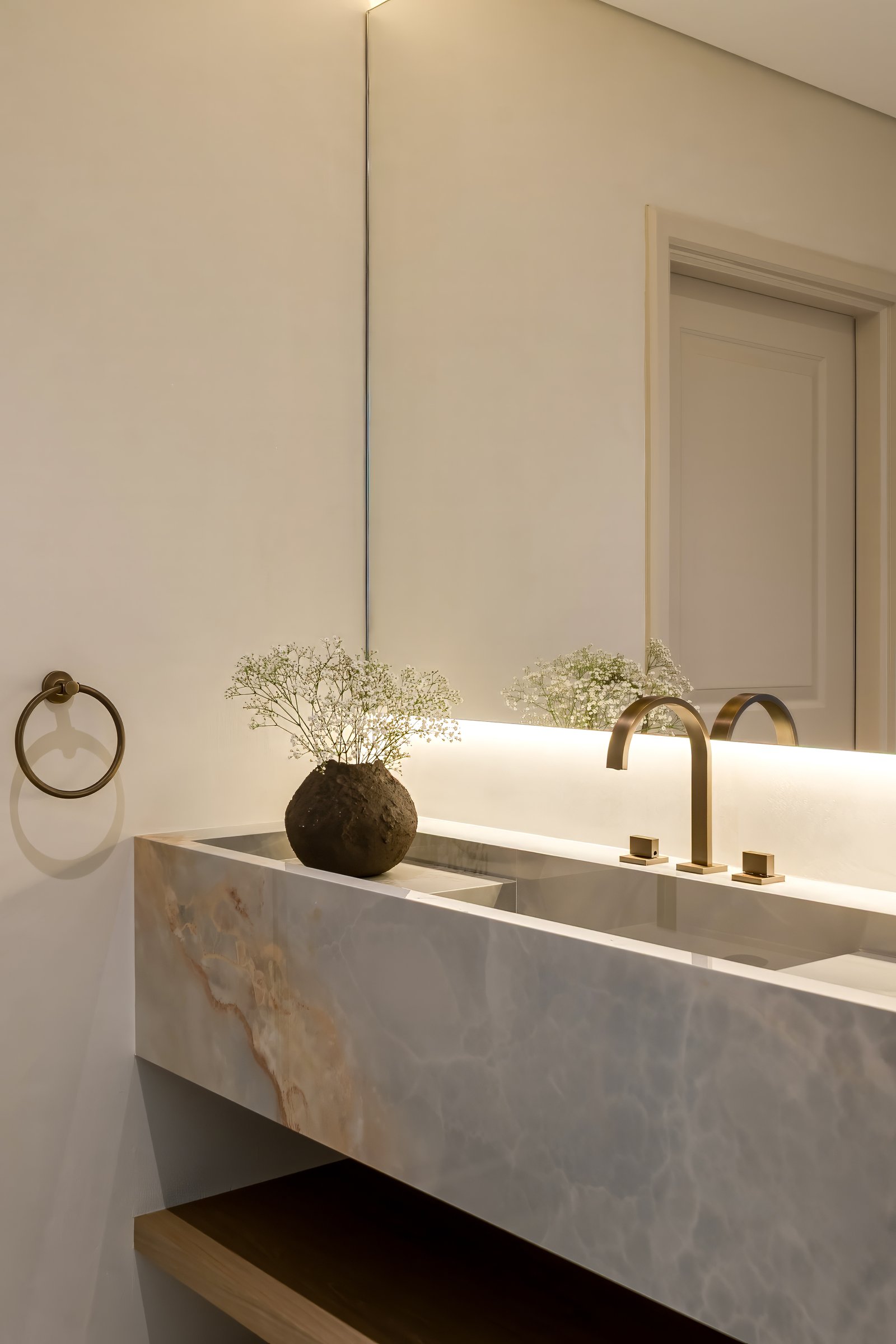 The powder room vanity is carved from onyx, backlit so the amber veining glows from within