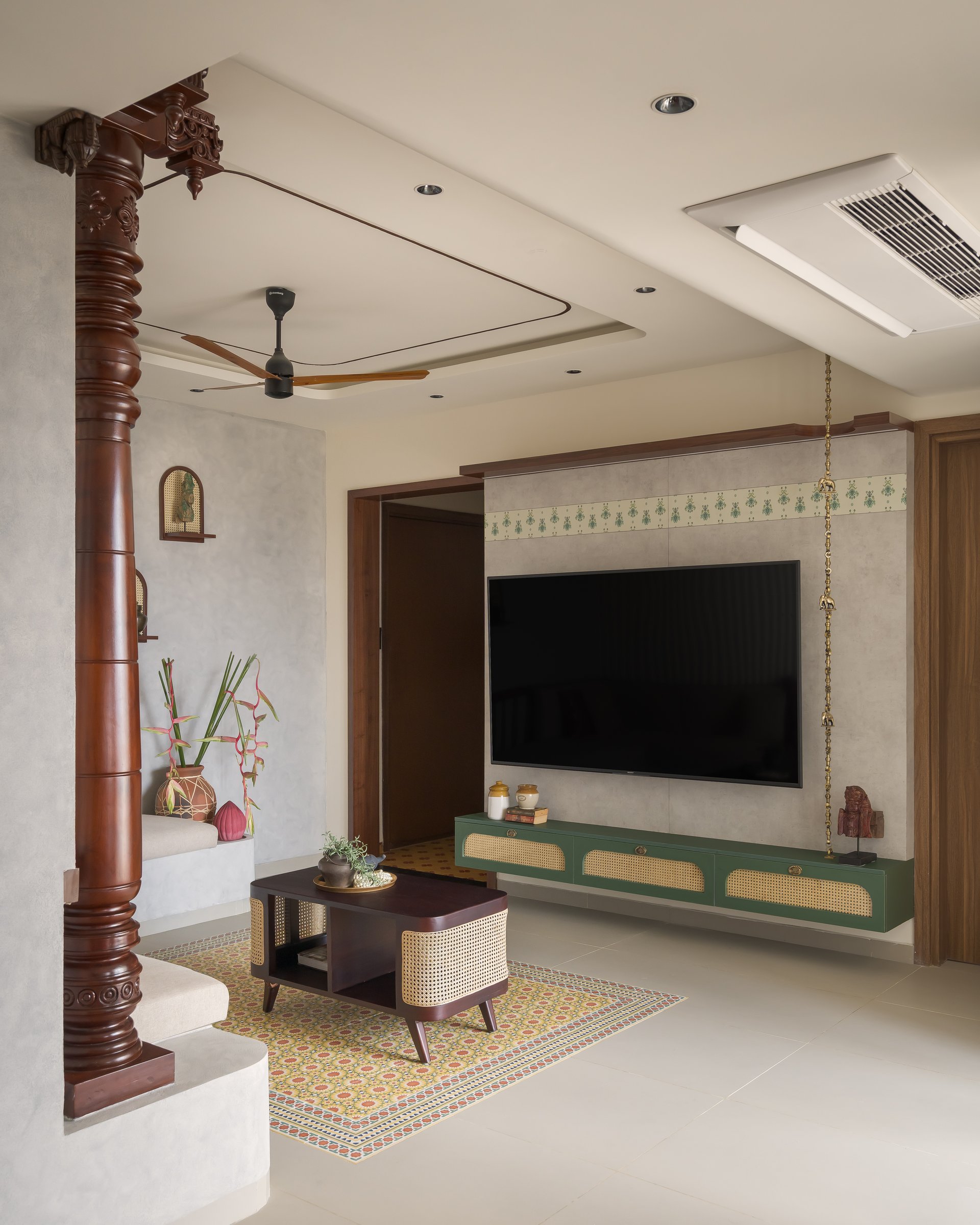 The living room, anchored by a carved wooden column and a floating vintage green console beneath a plastered media wall