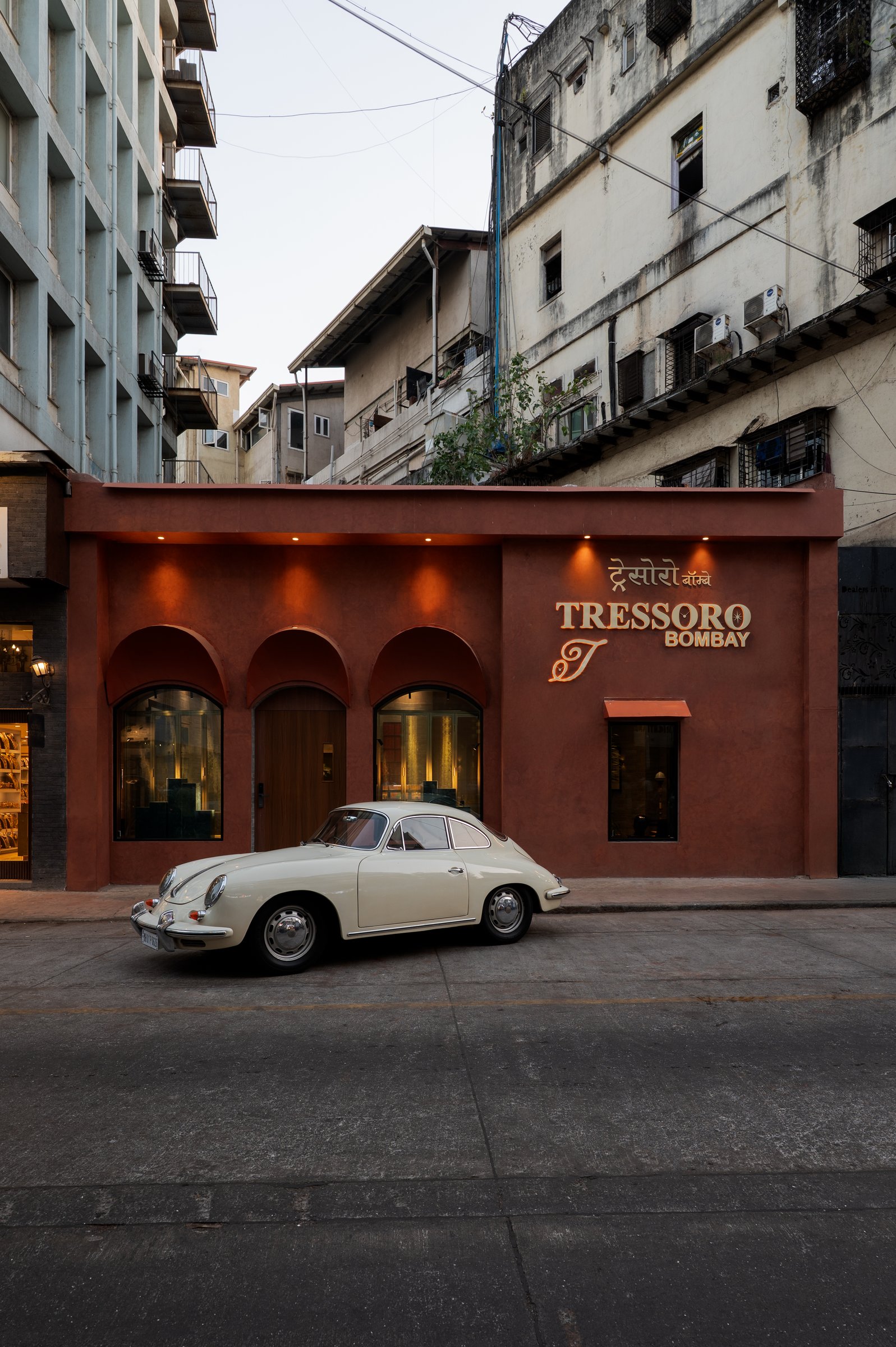 The reimagined facade on a Colaba street, three arched openings set into a deep terracotta-toned render