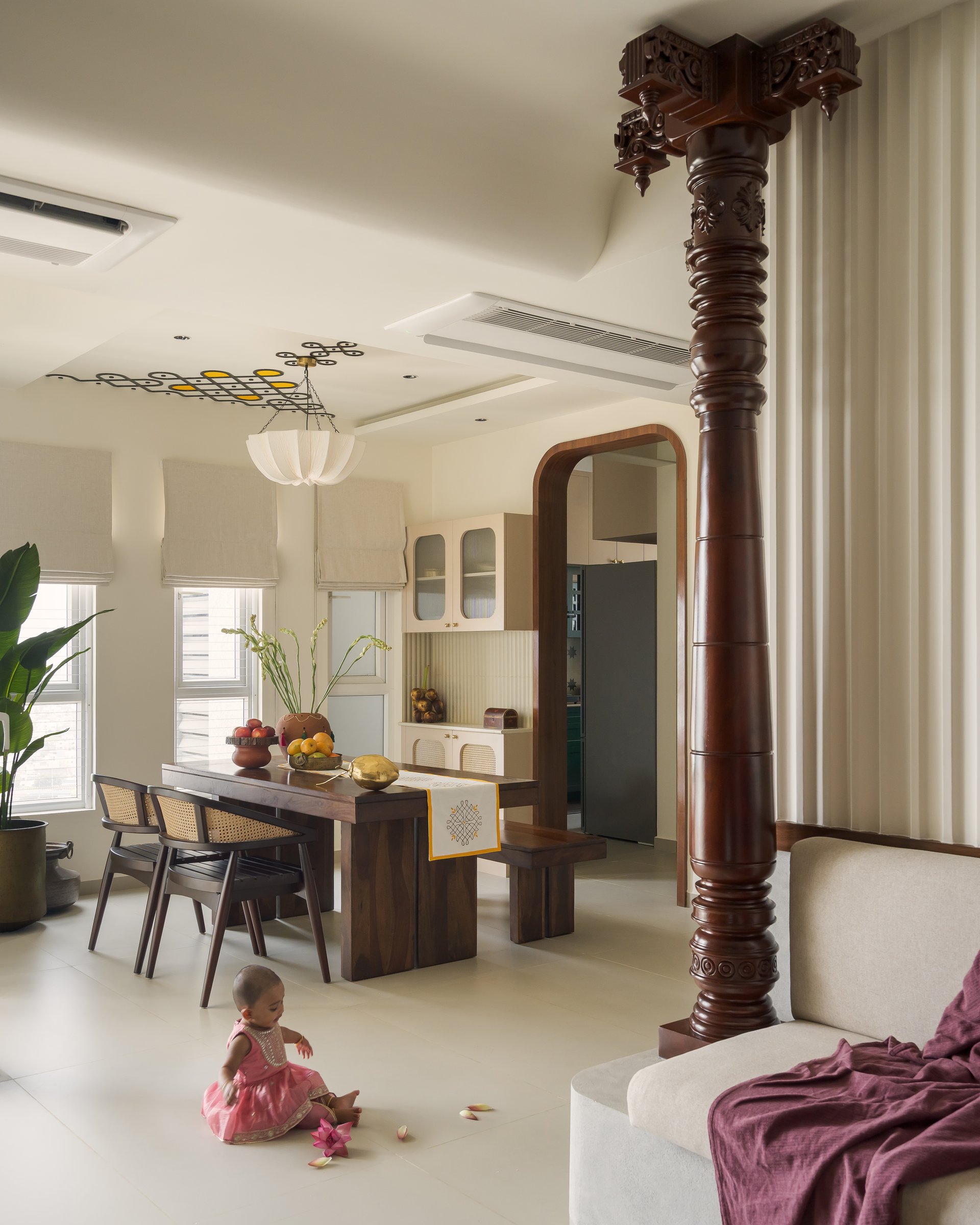 The dining zone, framed by the carved column and topped by a ceiling motif drawn from the kolam tradition