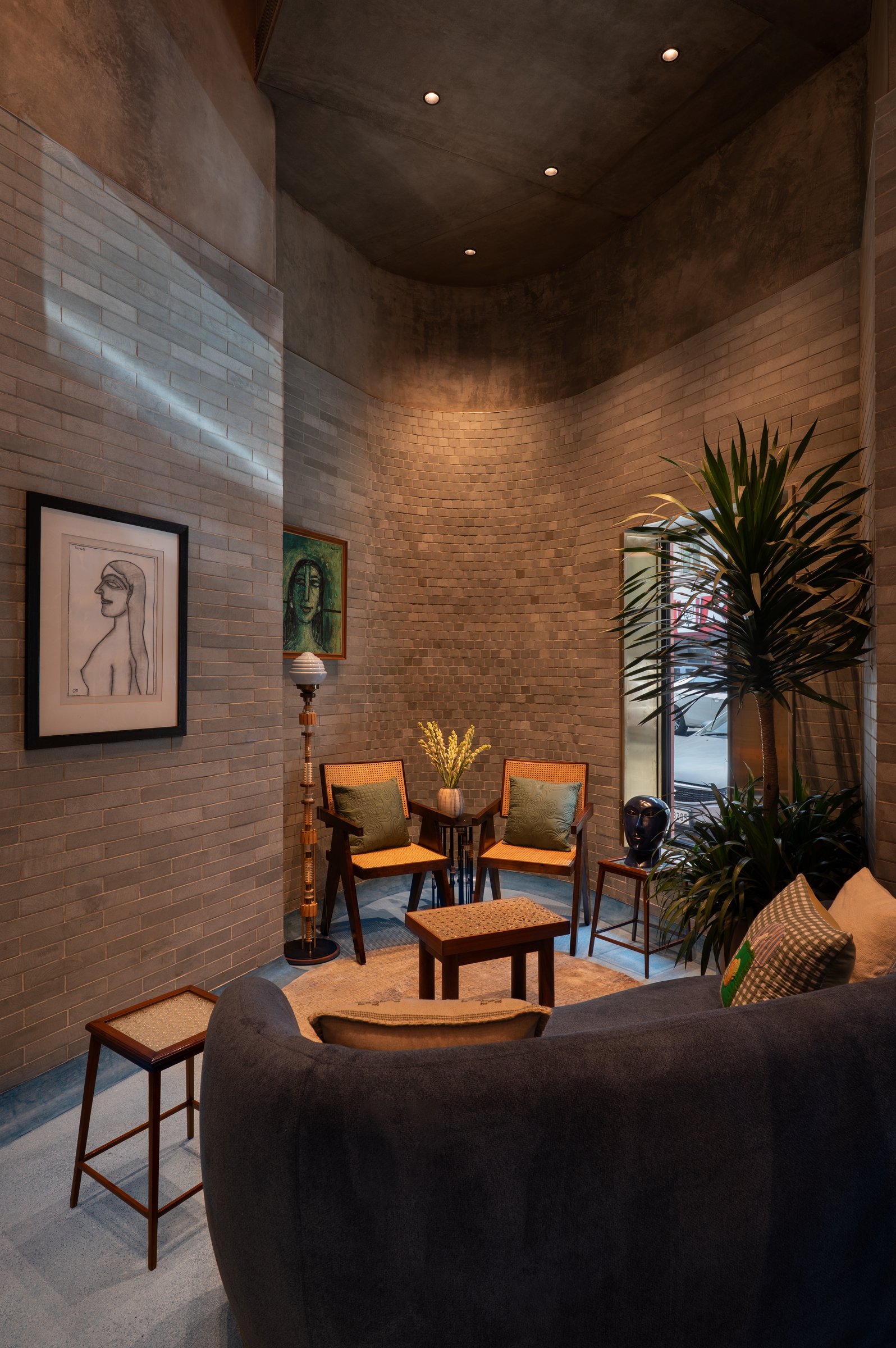 The tapered end of the plan, where the brick envelope curves into an intimate alcove furnished with a pair of caned lounge chairs