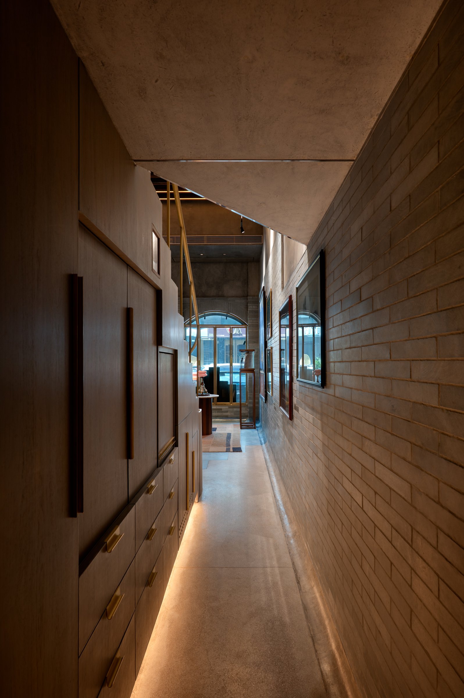 The service corridor behind the main retail space, its joinery wall lit by a discreet cove at the floor